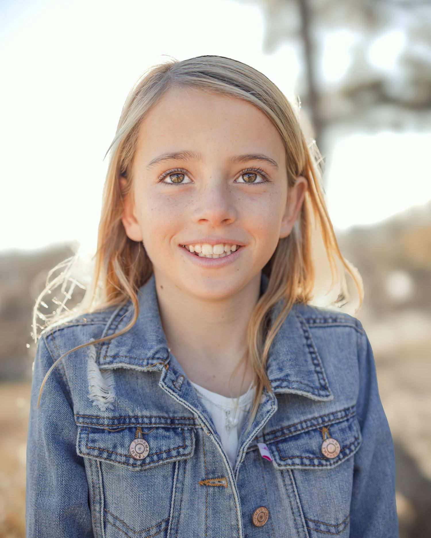 Three close-up portraits of a child wearing a denim jacket and smiling against a blurred outdoor background.