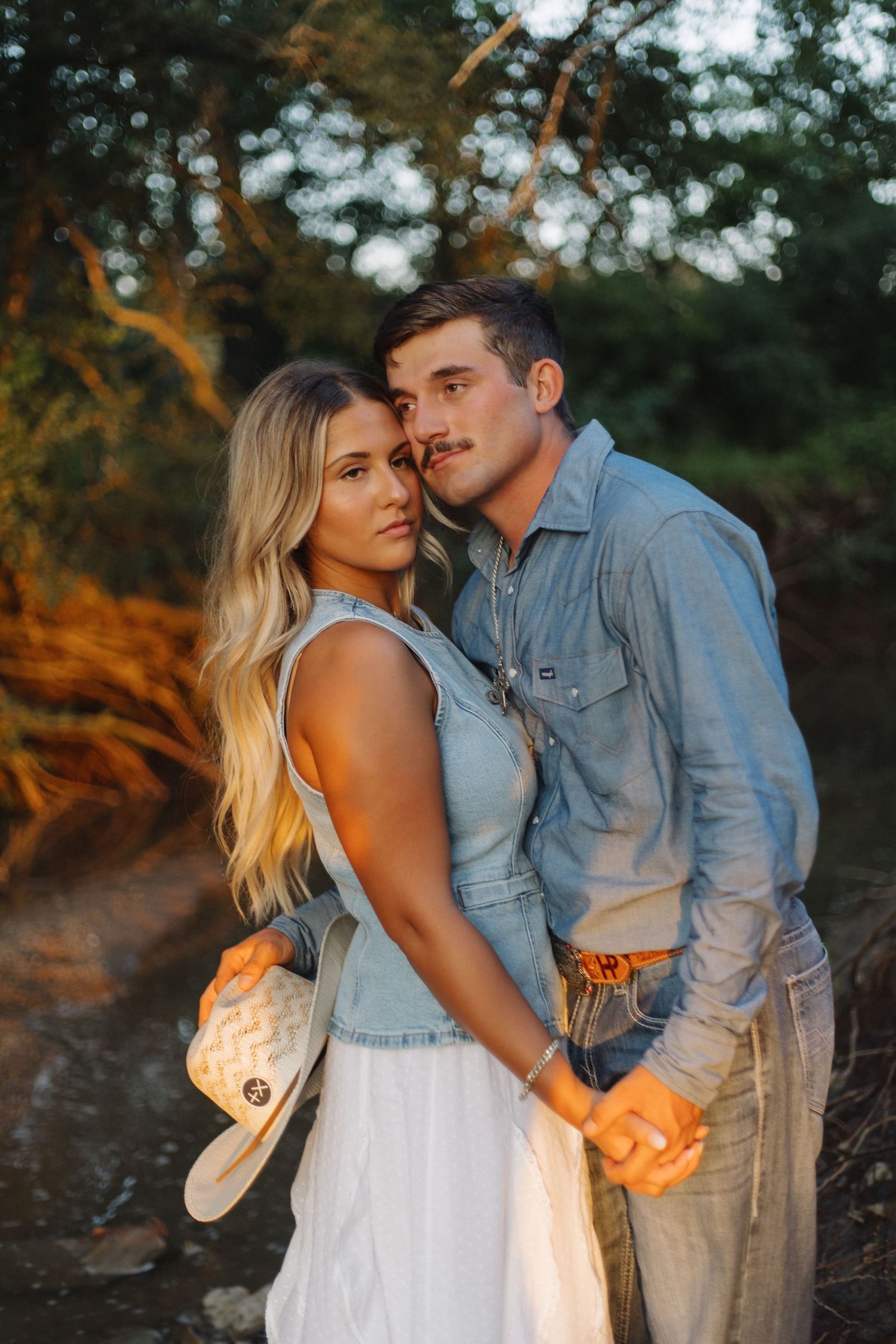 Couple in matching denim outfits sharing intimate moment at sunset.