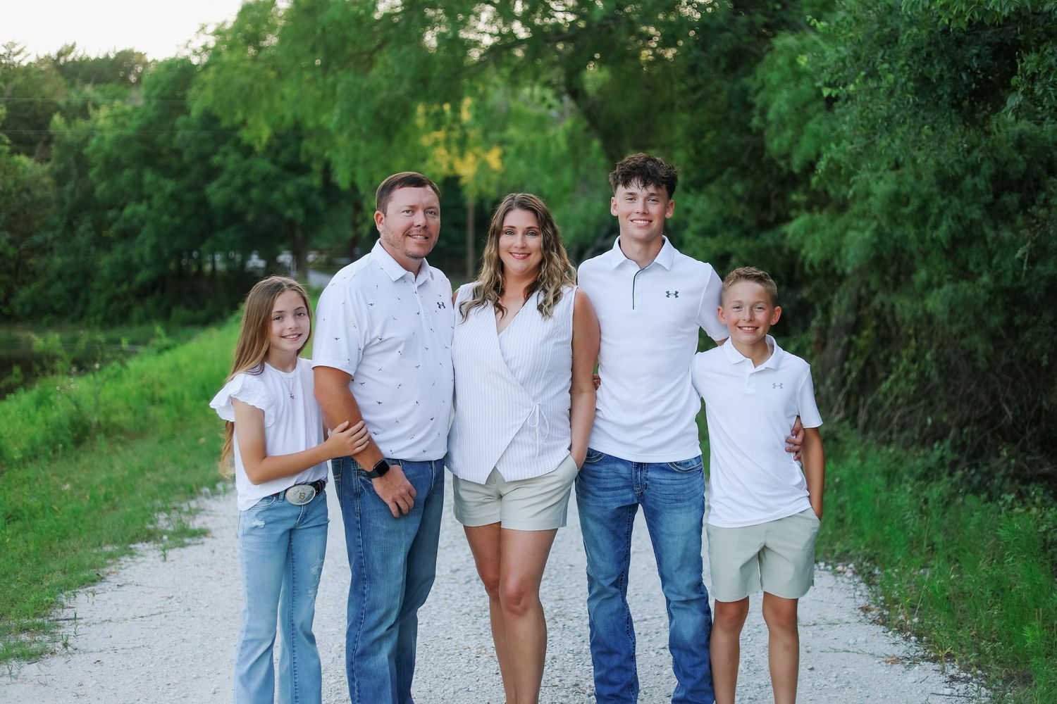 Family walking together on a tree-lined path wearing coordinated blue and white outfits.