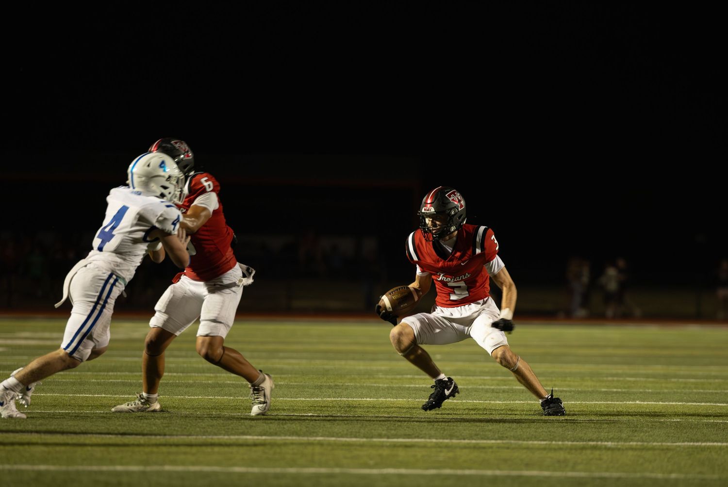 Football players engaged in an intense play during a night game on the field.