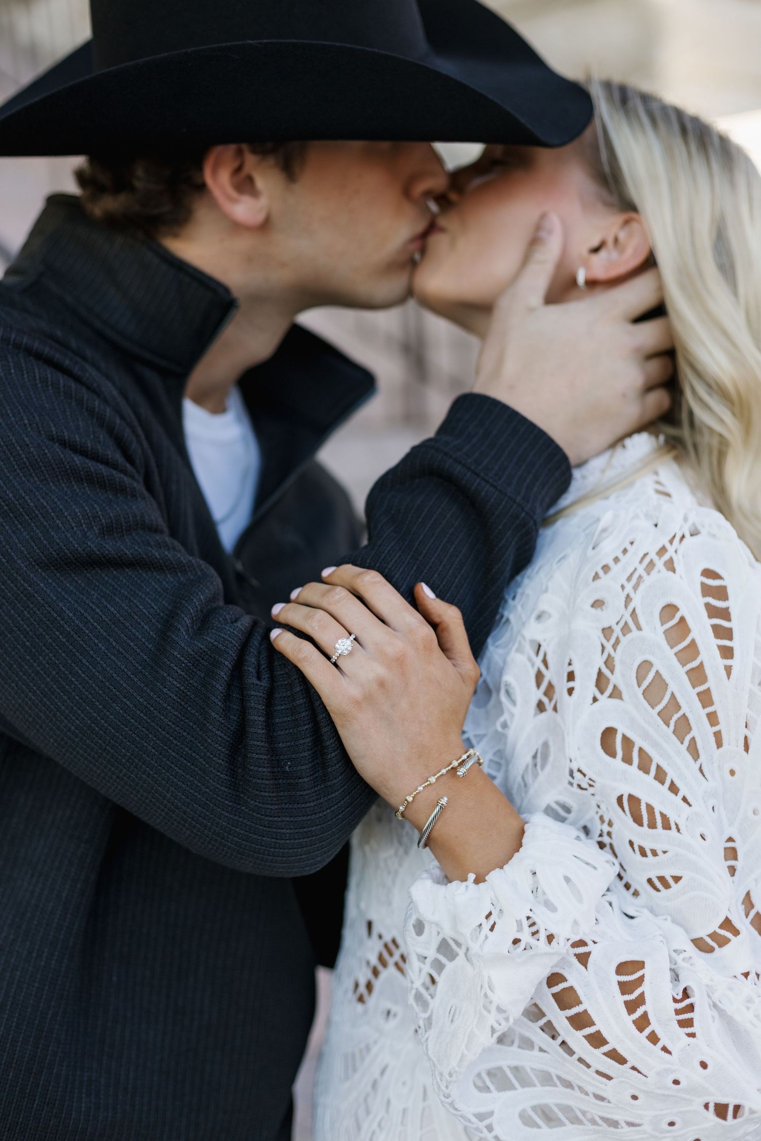 Romantic couple in white lace dress and black sweater sharing intimate moment.