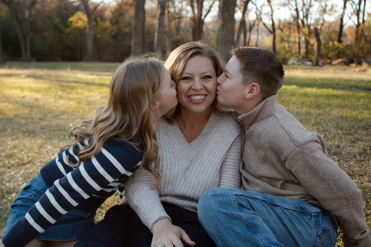 Family shares loving embraces while sitting together outdoors.