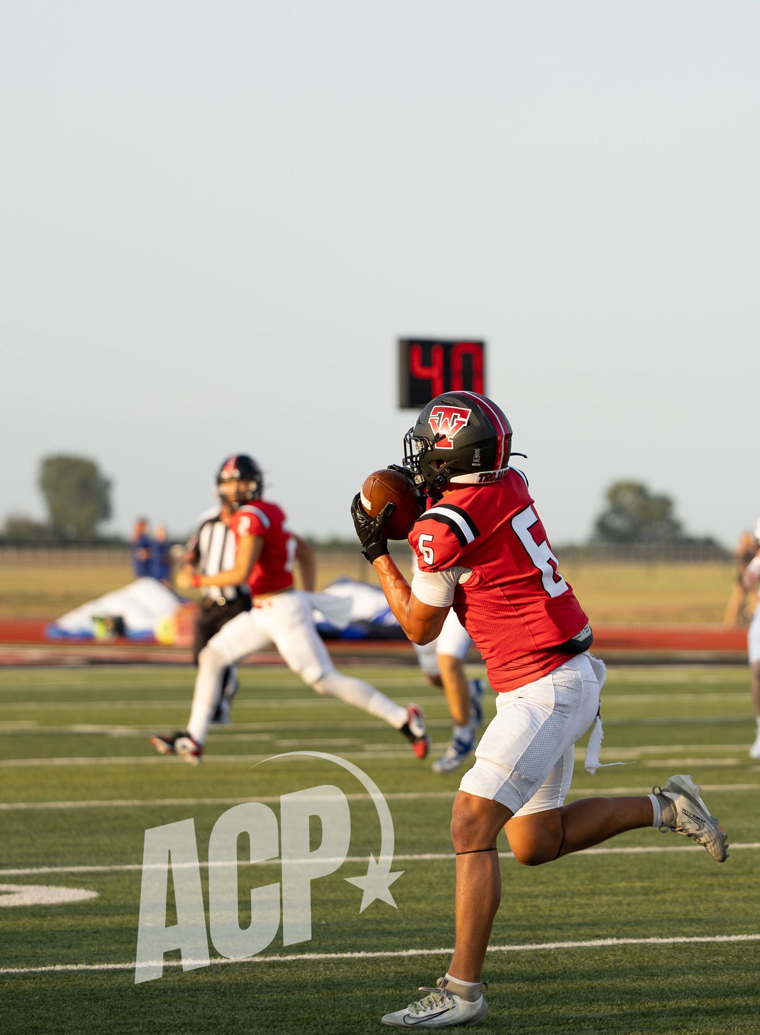 Football players in red jerseys diving and making plays on the field during a game.