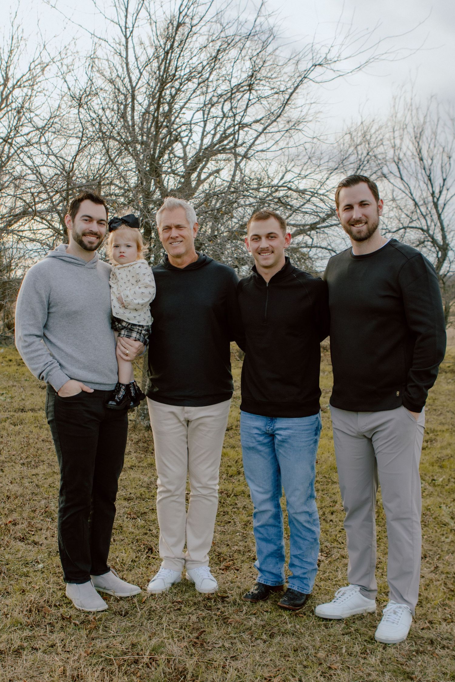 Group photo session outdoors with family members wearing casual clothing in winter setting.