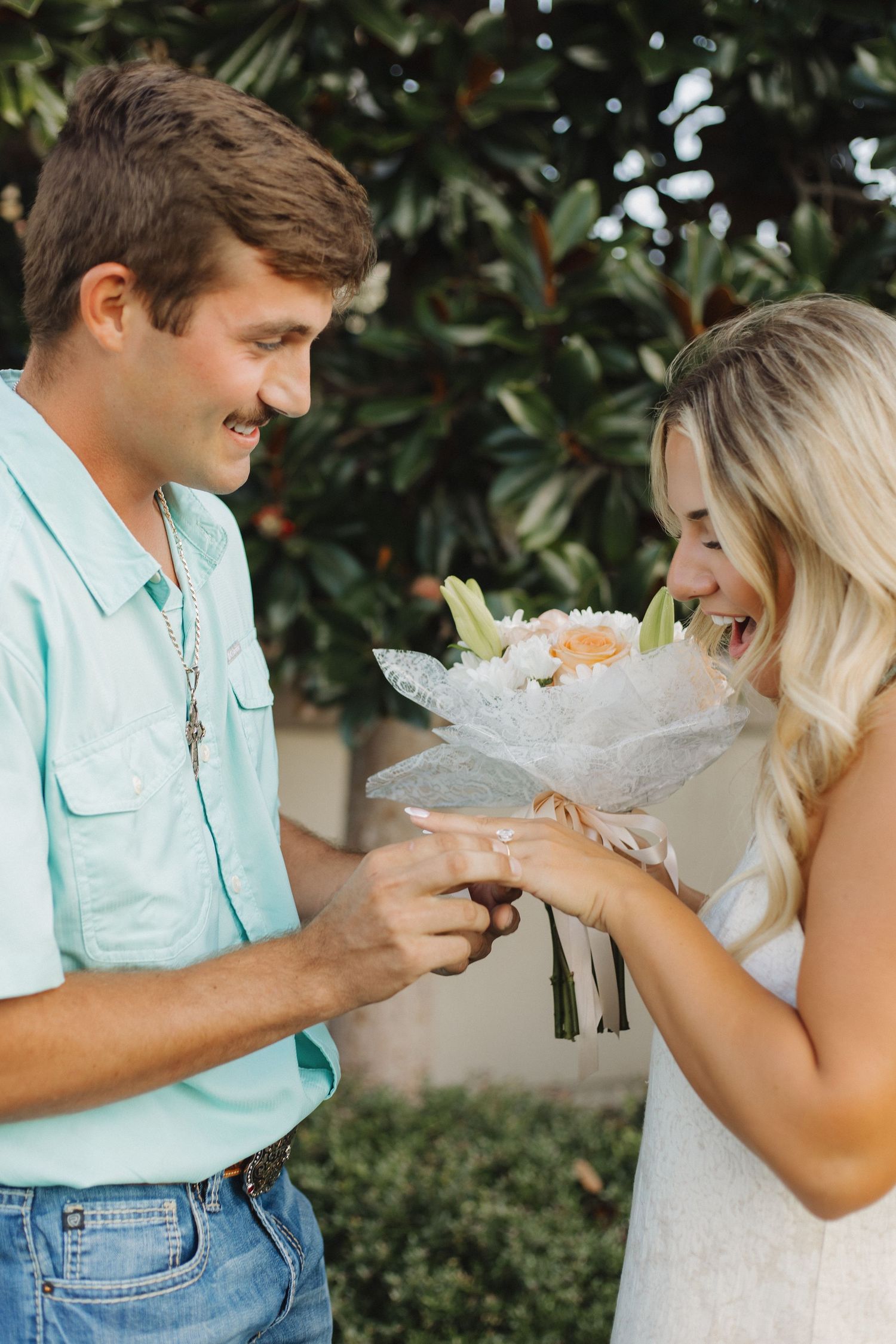 Couple joyfully celebrating their engagement in a garden setting.