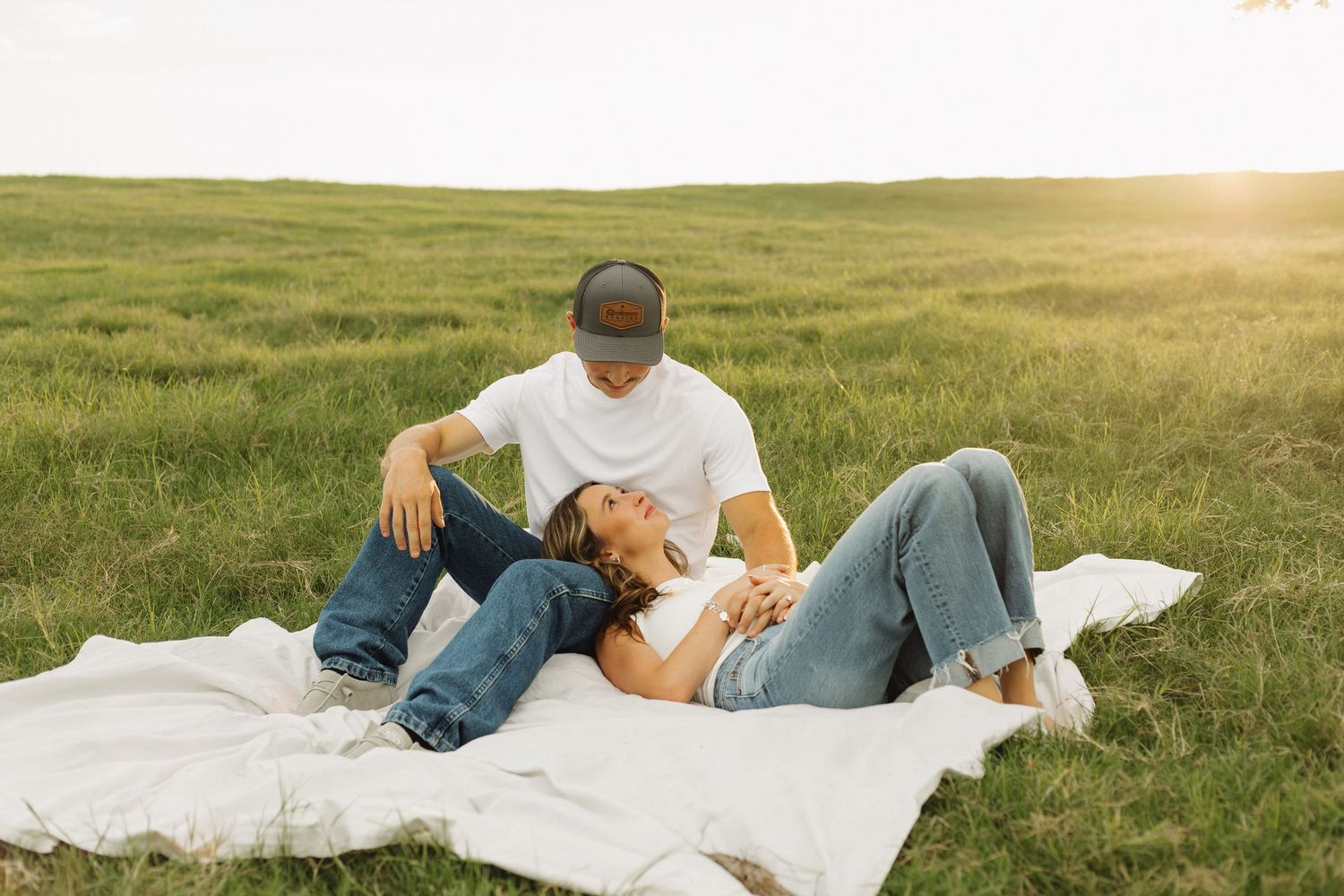 Couple relaxing together on a picnic blanket in a sunlit meadow.
