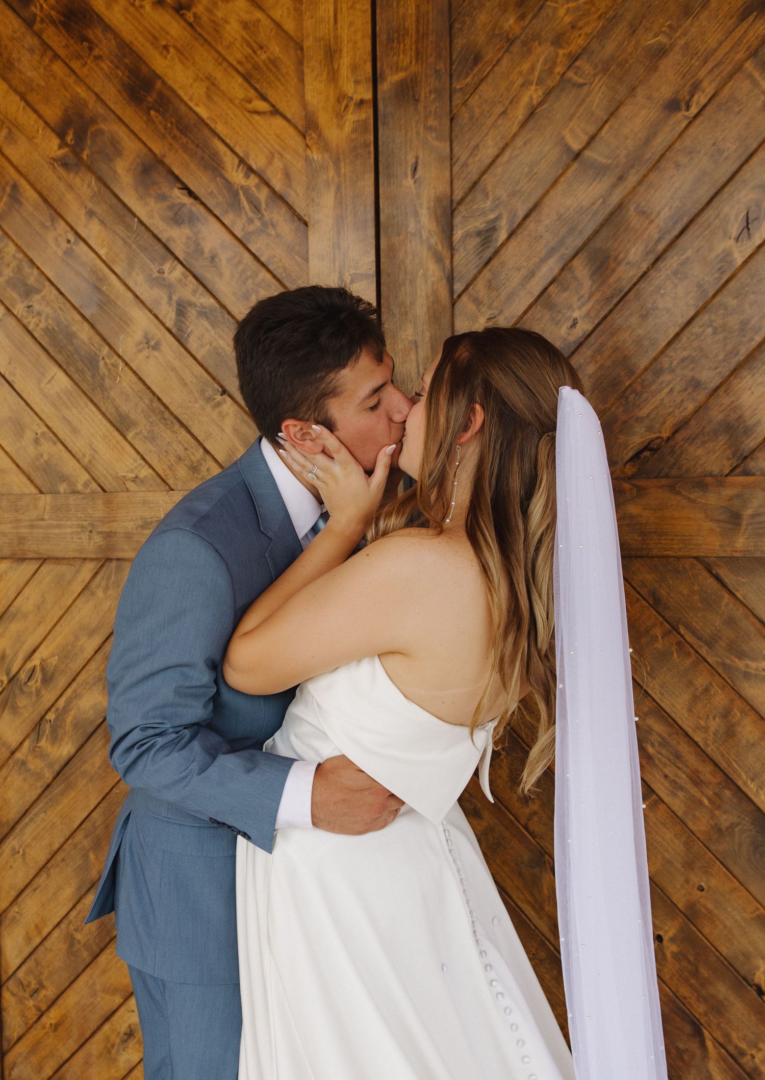 Romantic moment captured against rustic wooden barn wall backdrop.