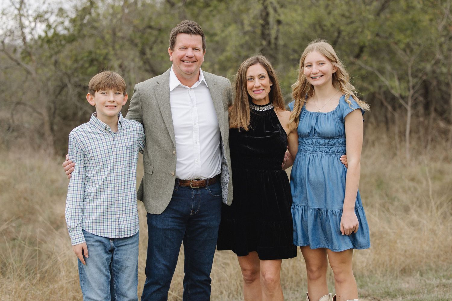 Family members smiling together during an outdoor photo session in a natural setting.