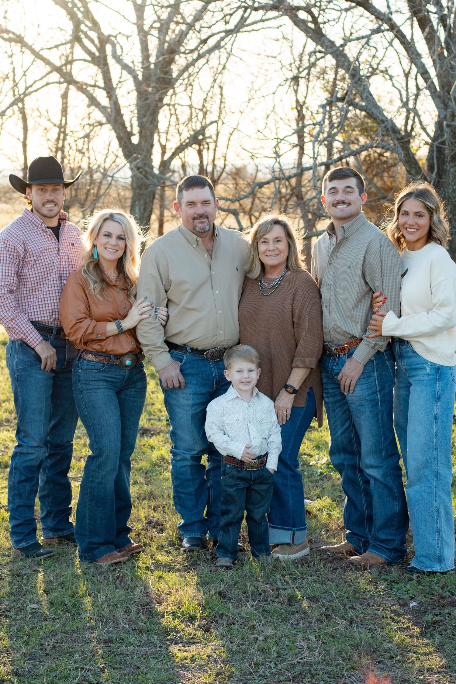 Large family group in coordinated casual outfits poses for outdoor portrait.