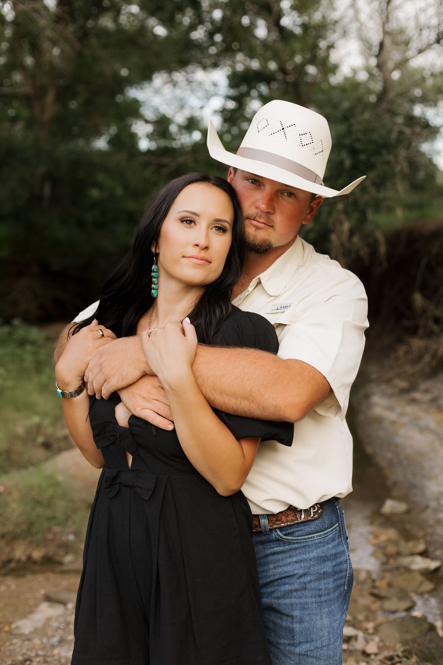 A romantic photoshoot series showing a couple embracing outdoors, with her in a black dress and him in western attire.