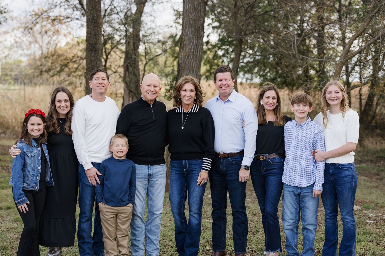 Large family group wearing coordinated blue and white outfits posing outdoors for a portrait.