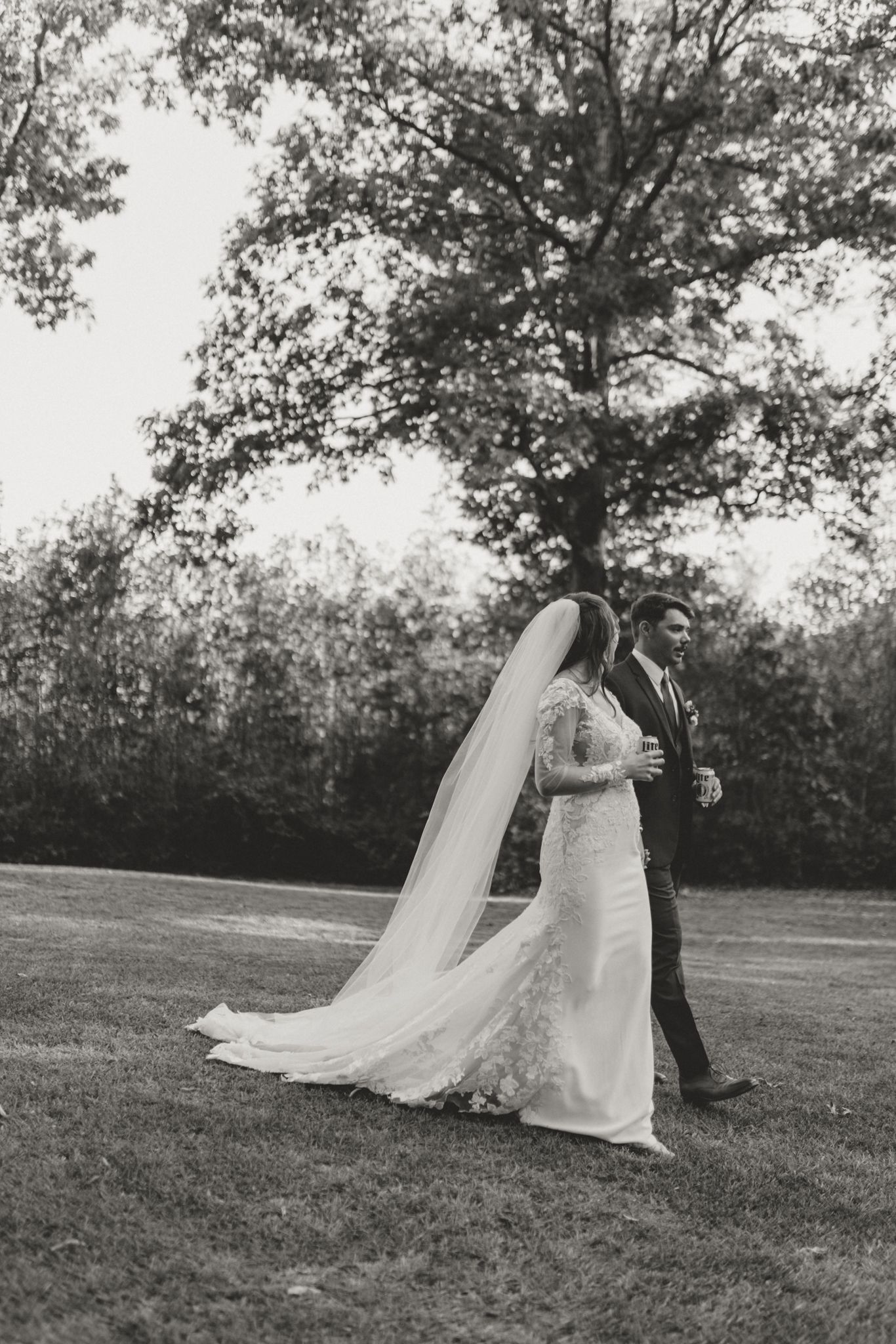 Wedding couple dancing gracefully across a grassy field in timeless black and white.