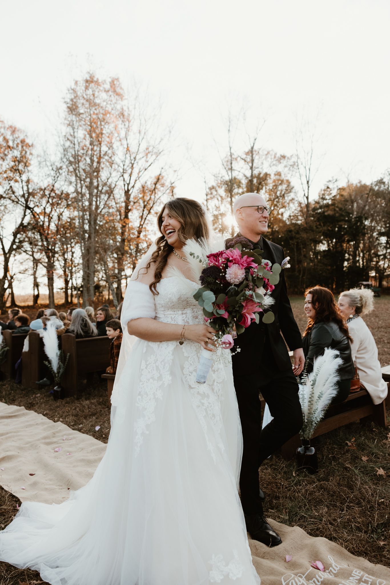 A joyful wedding recessional moment captured during golden hour with autumn foliage.