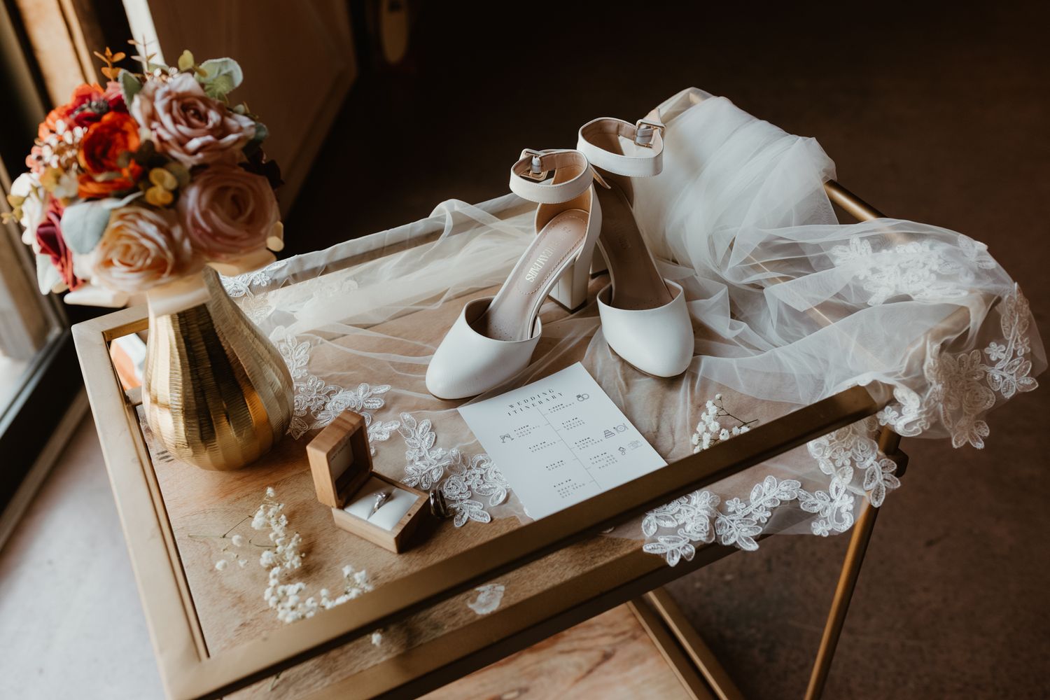 Artistic rustic table setting with scattered wedding lace veil and stationery elements in warm lighting.
