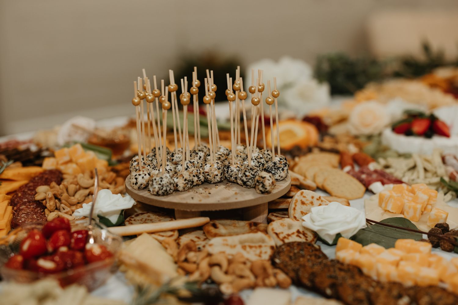 Elegant appetizer table with silver toothpicks and assorted finger foods arranged on a grazing board.