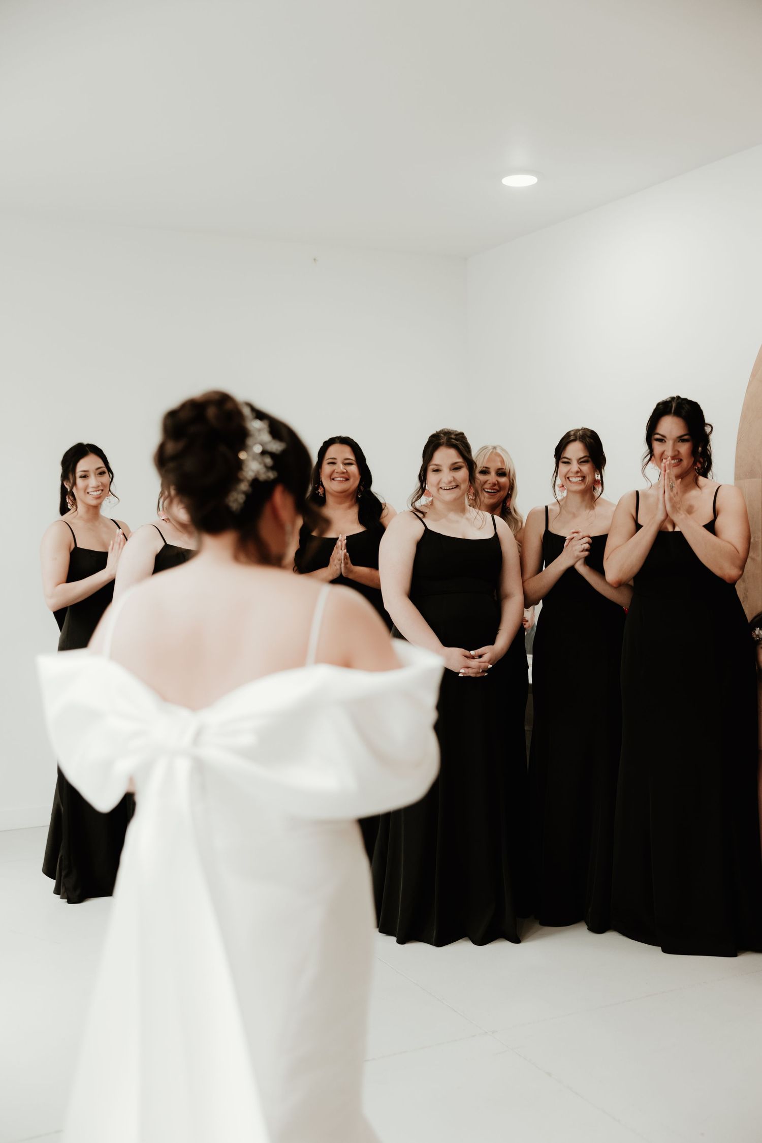 Wedding party scene with bridesmaids in black dresses posing with bride in white.