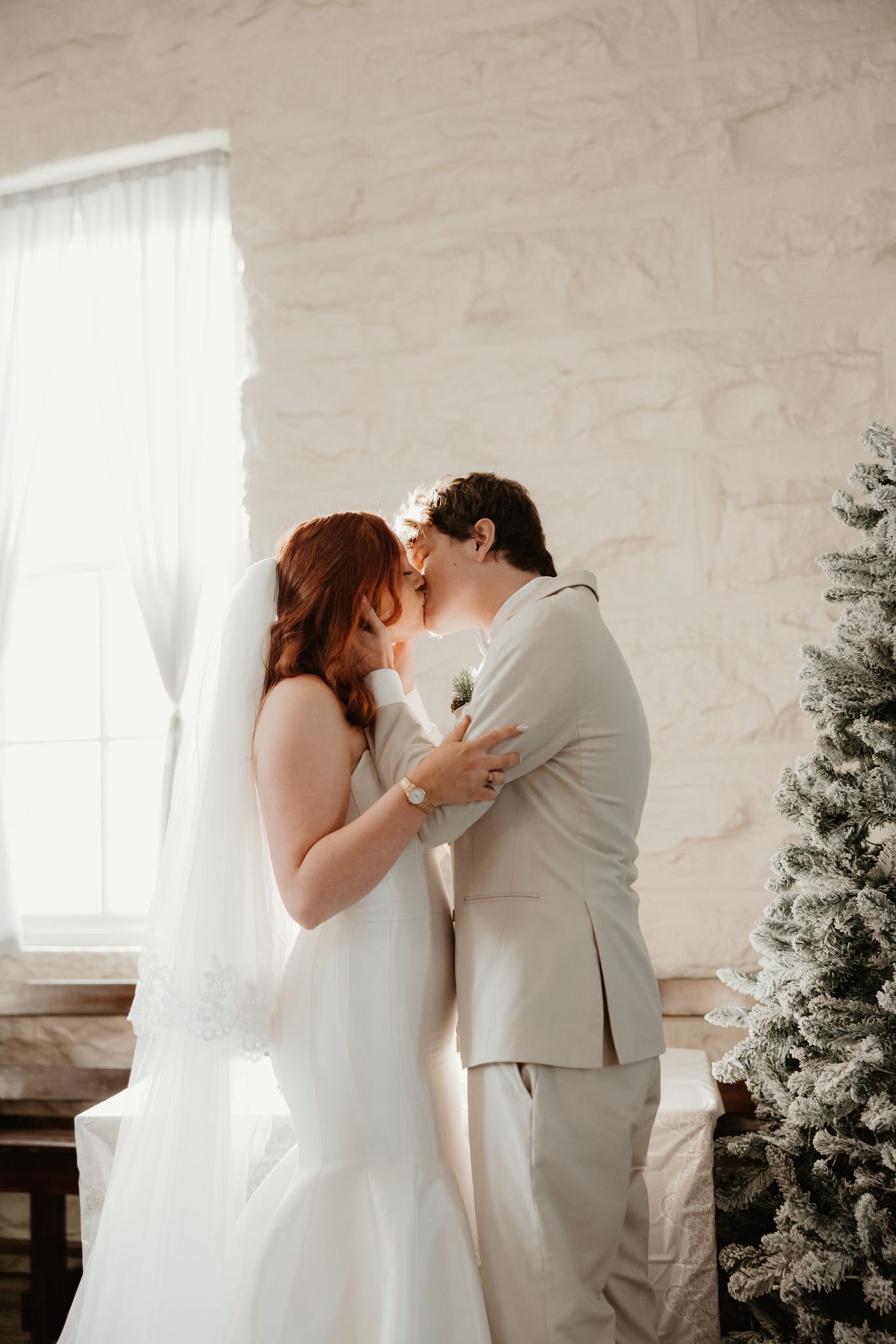 An intimate wedding moment captured against white stone walls and winter decor.
