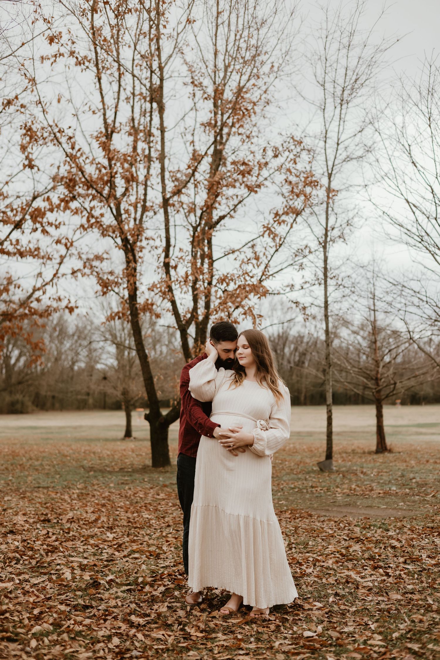 A couple sharing a tender moment outdoors surrounded by fall foliage.