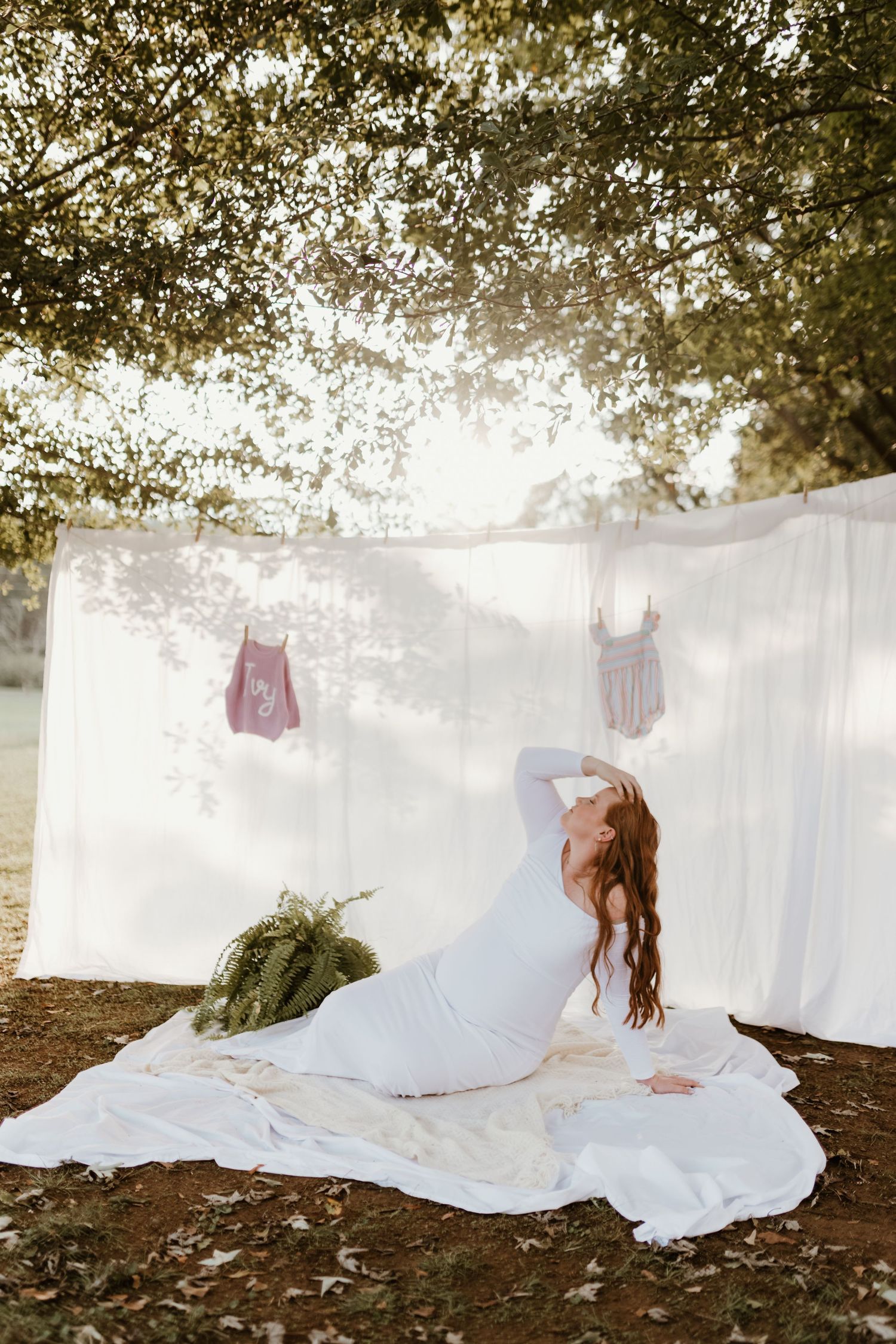 Ethereal lifestyle photoshoot with flowing white sheets and dresses hung on a clothesline in a dreamy outdoor setting.