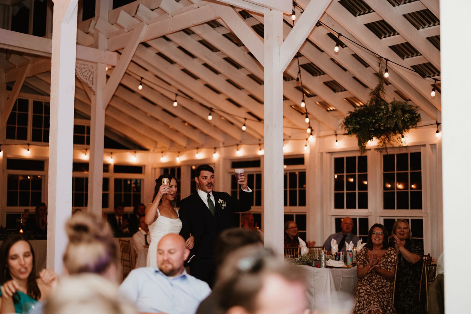 Reception venue with white lattice ceiling and string lights during evening celebration.