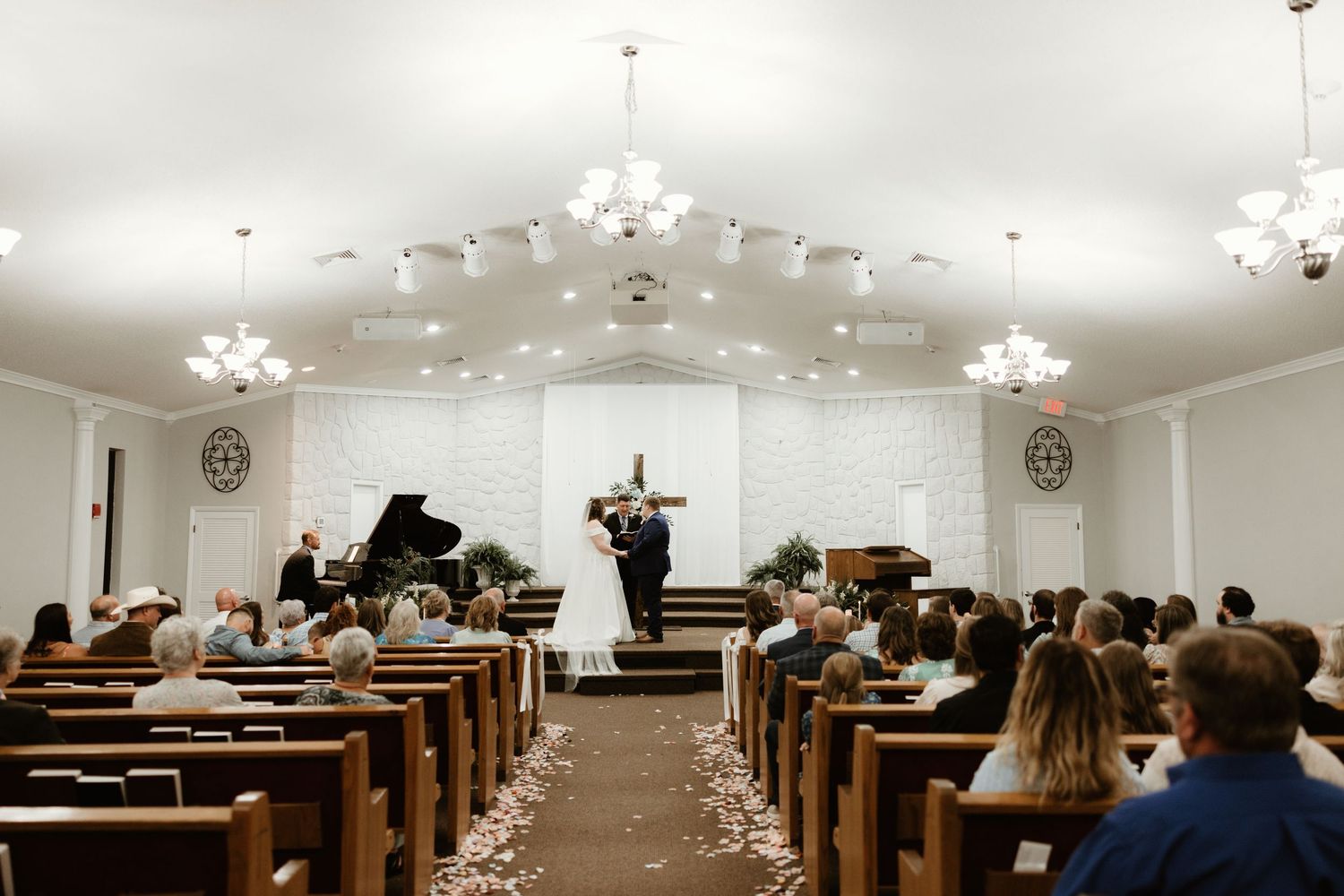Musician performs on stage in a white church sanctuary with pews filled by audience members during a concert performance.