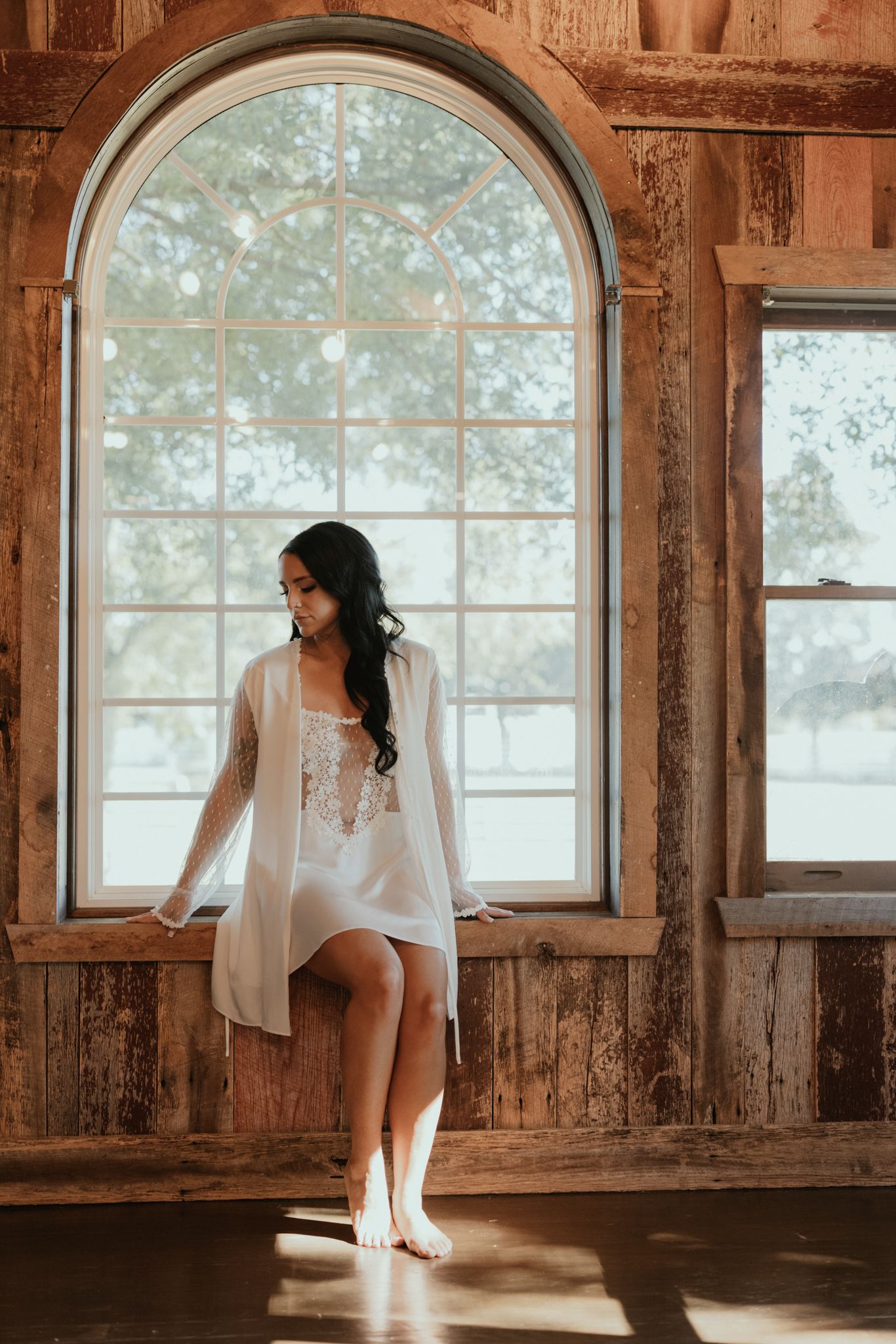 White lingerie and robe photographed in front of a rustic arched window with natural light.