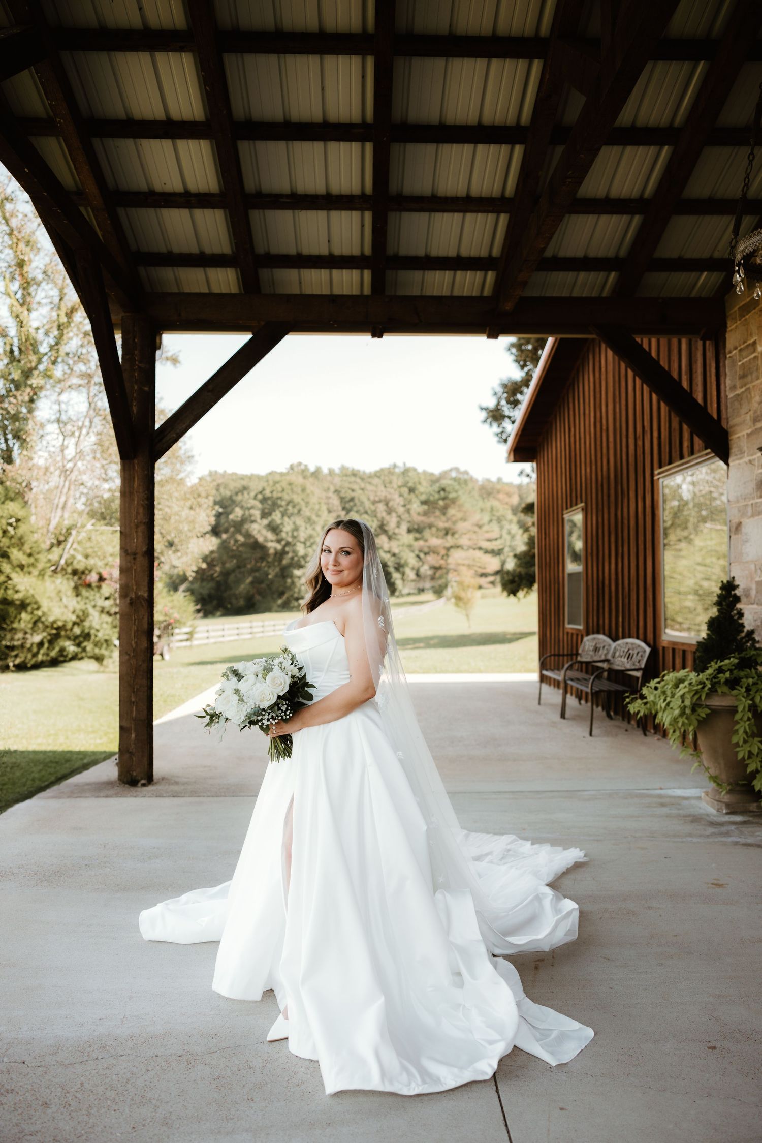 A wedding gown twirls in a rustic covered venue with wooden posts and natural outdoor backdrop.