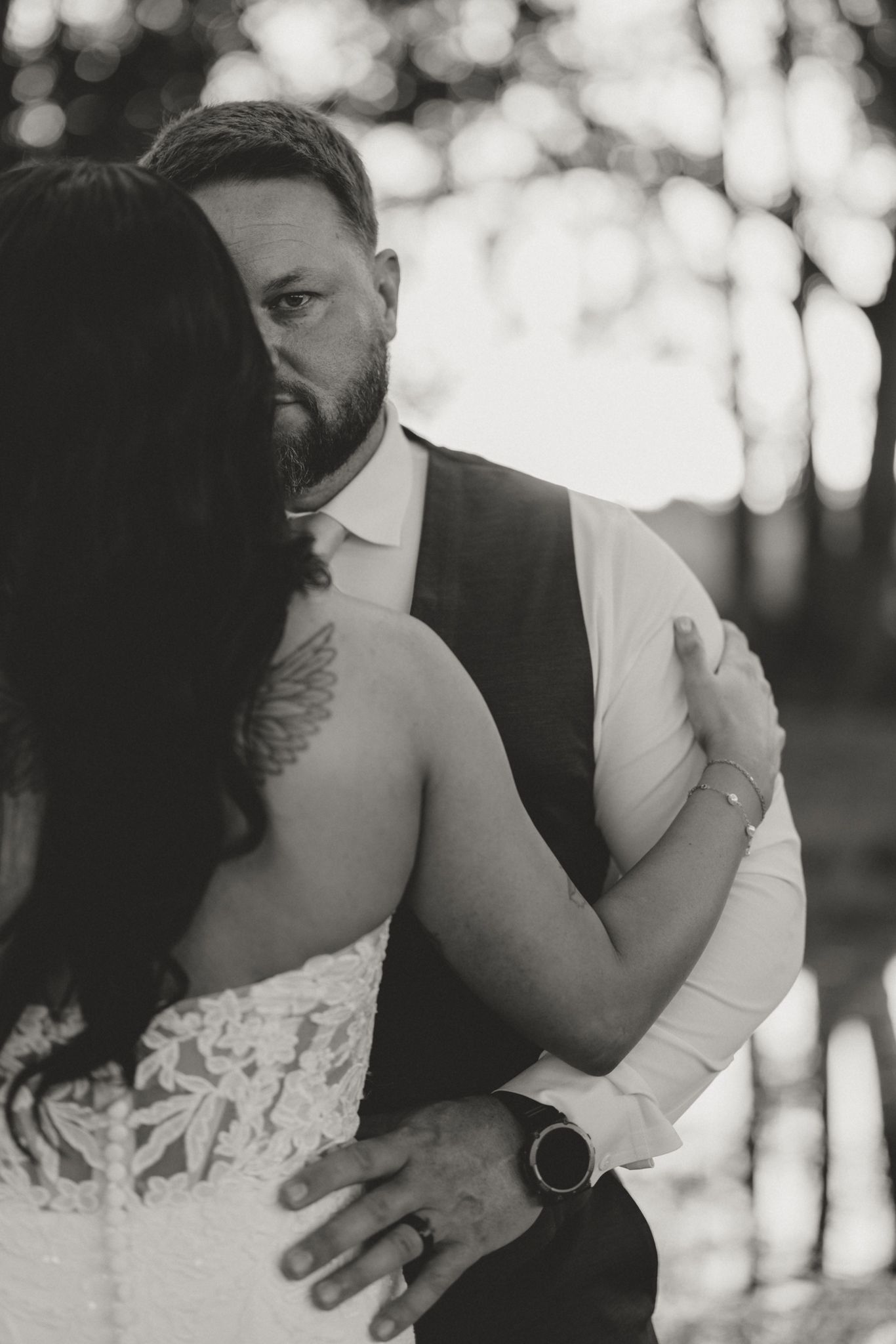 Black and white intimate wedding portrait showing a tender embrace in soft bokeh lighting.