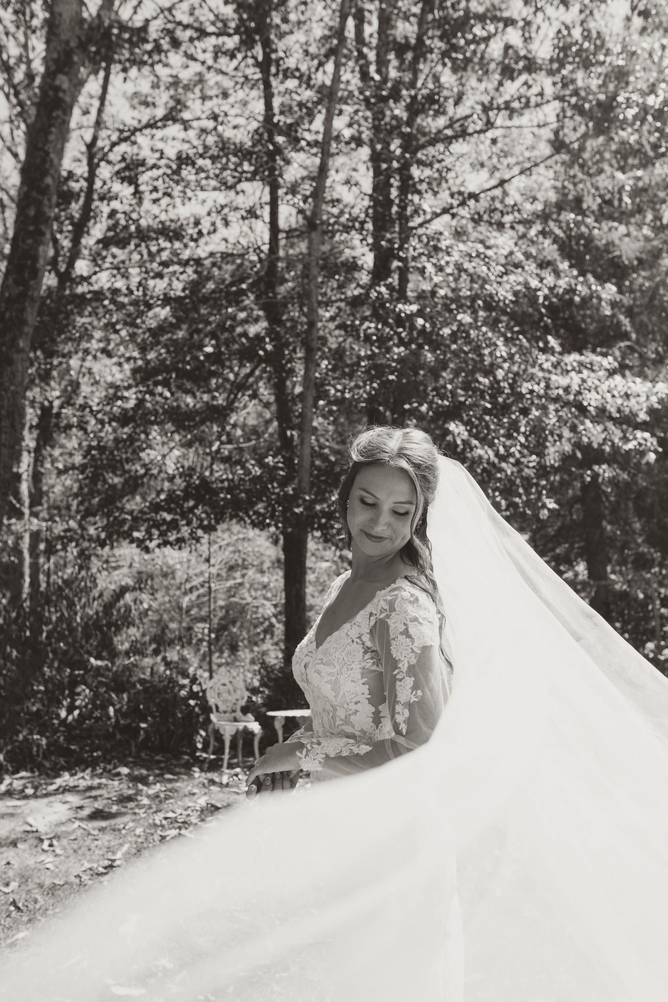 A close-up portrait of someone wearing an ornate white wedding dress in a wooded outdoor setting.