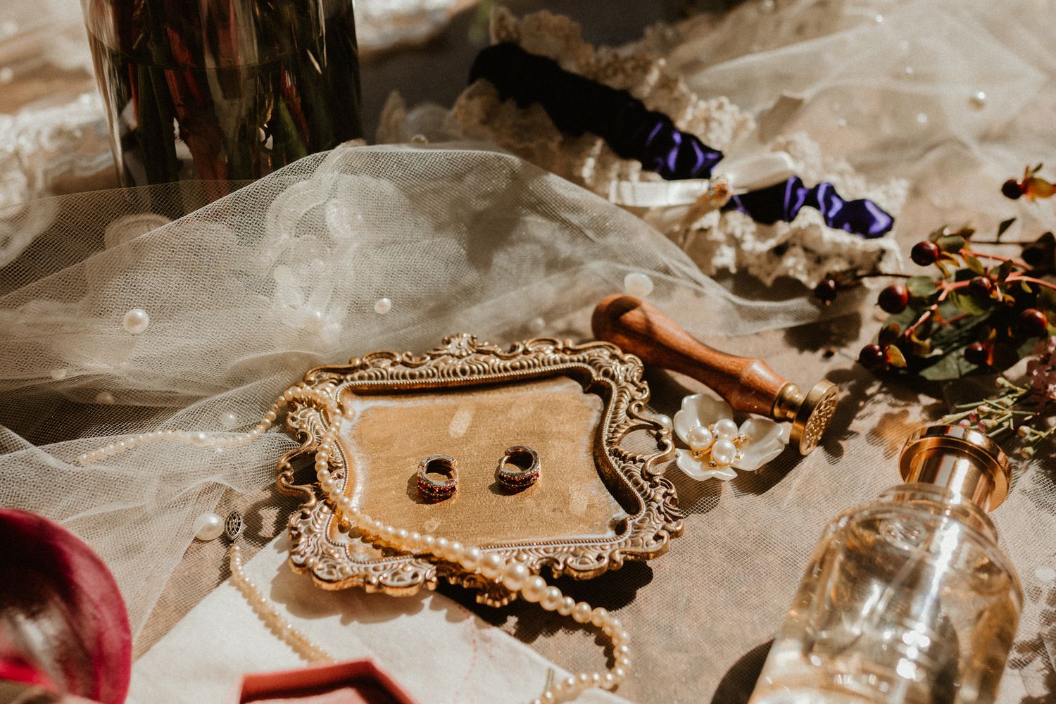 A curated collection of vintage jewelry, accessories, and antique trinkets displayed on textured cream-colored fabric.