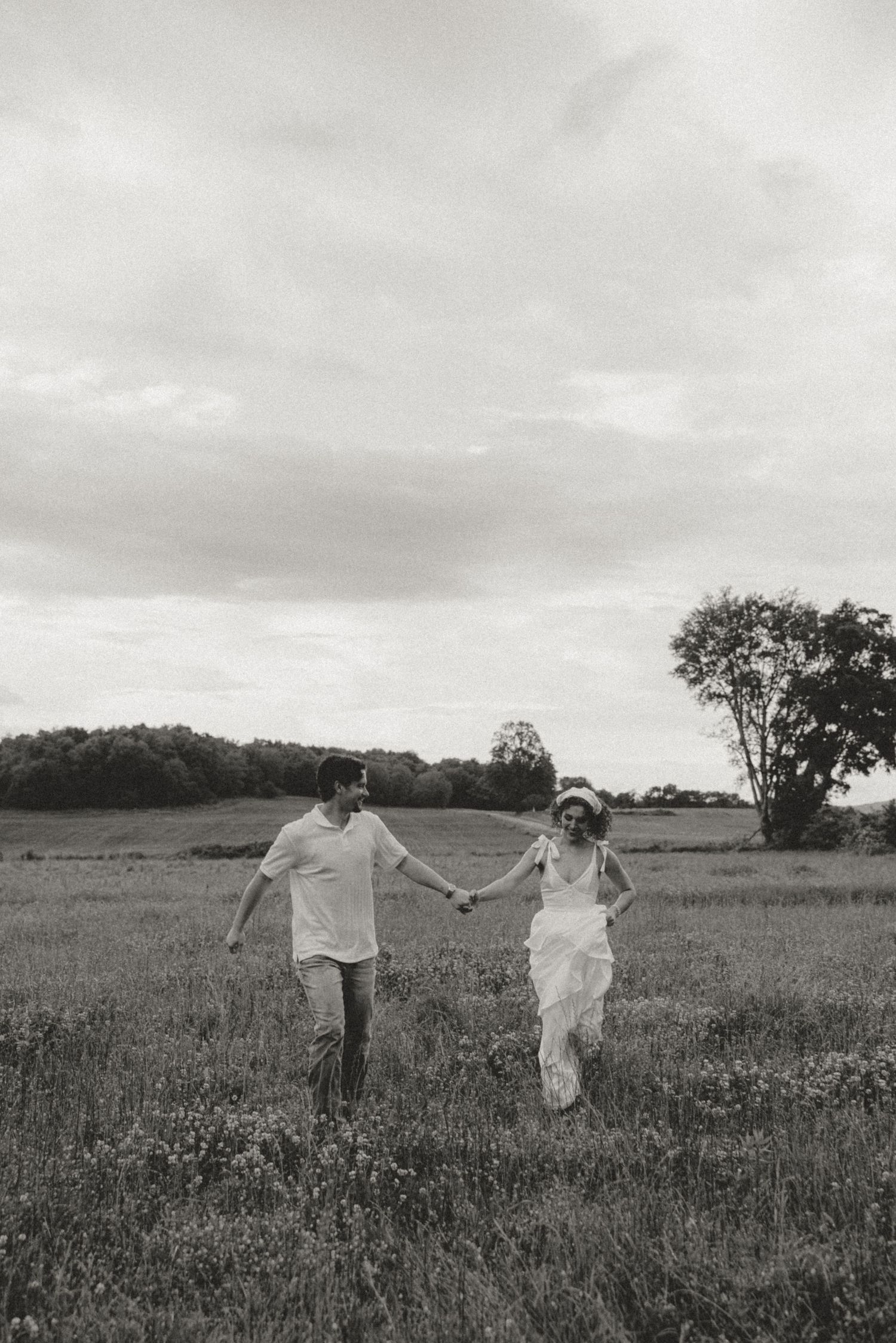 Couple running and dancing through a wildflower field on an overcast day.