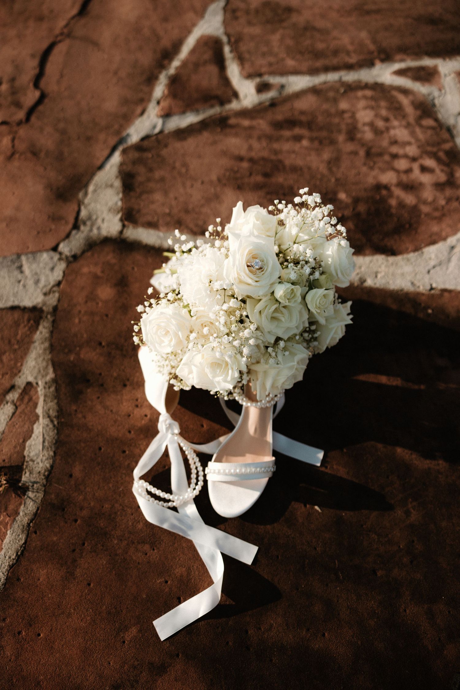 White floral bouquet with ribbons artistically arranged on a rustic brown textured surface.