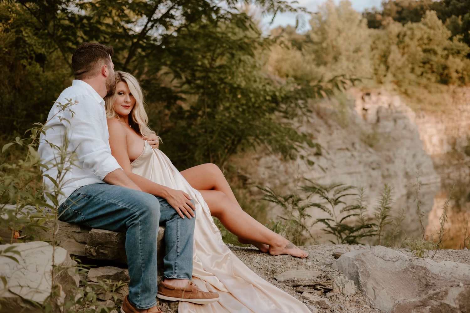Couple posing together in casual attire on rocky terrain during sunset.