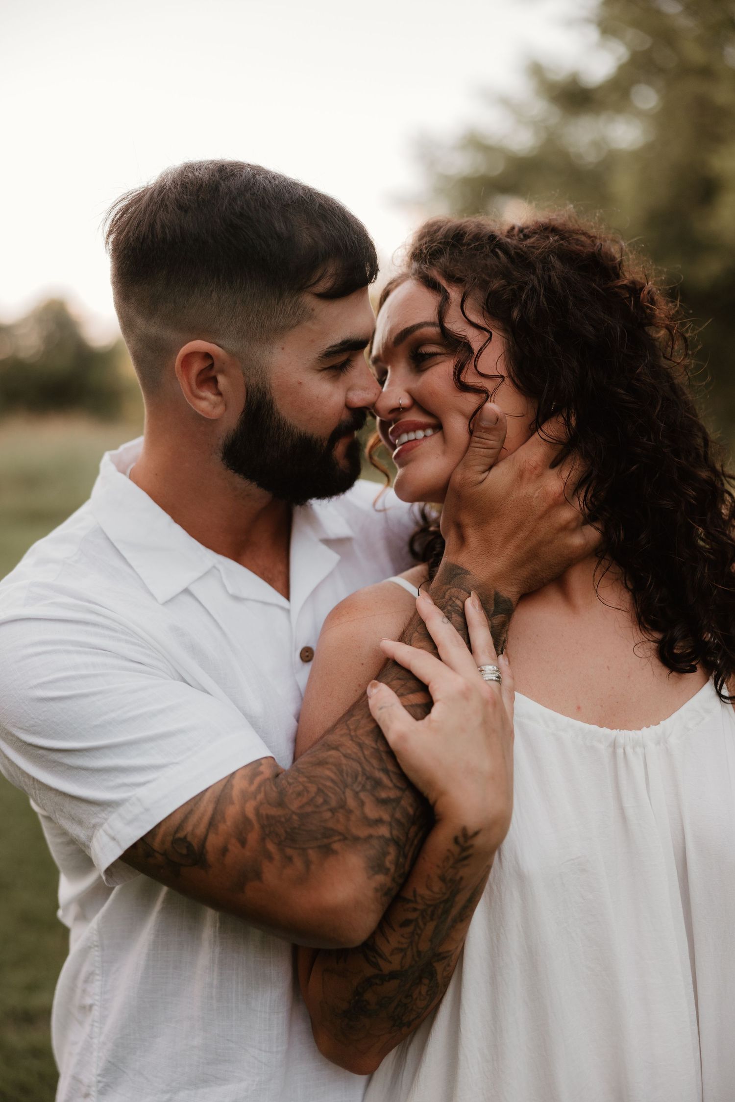 Intimate outdoor couple photoshoot with white outfits and natural lighting.