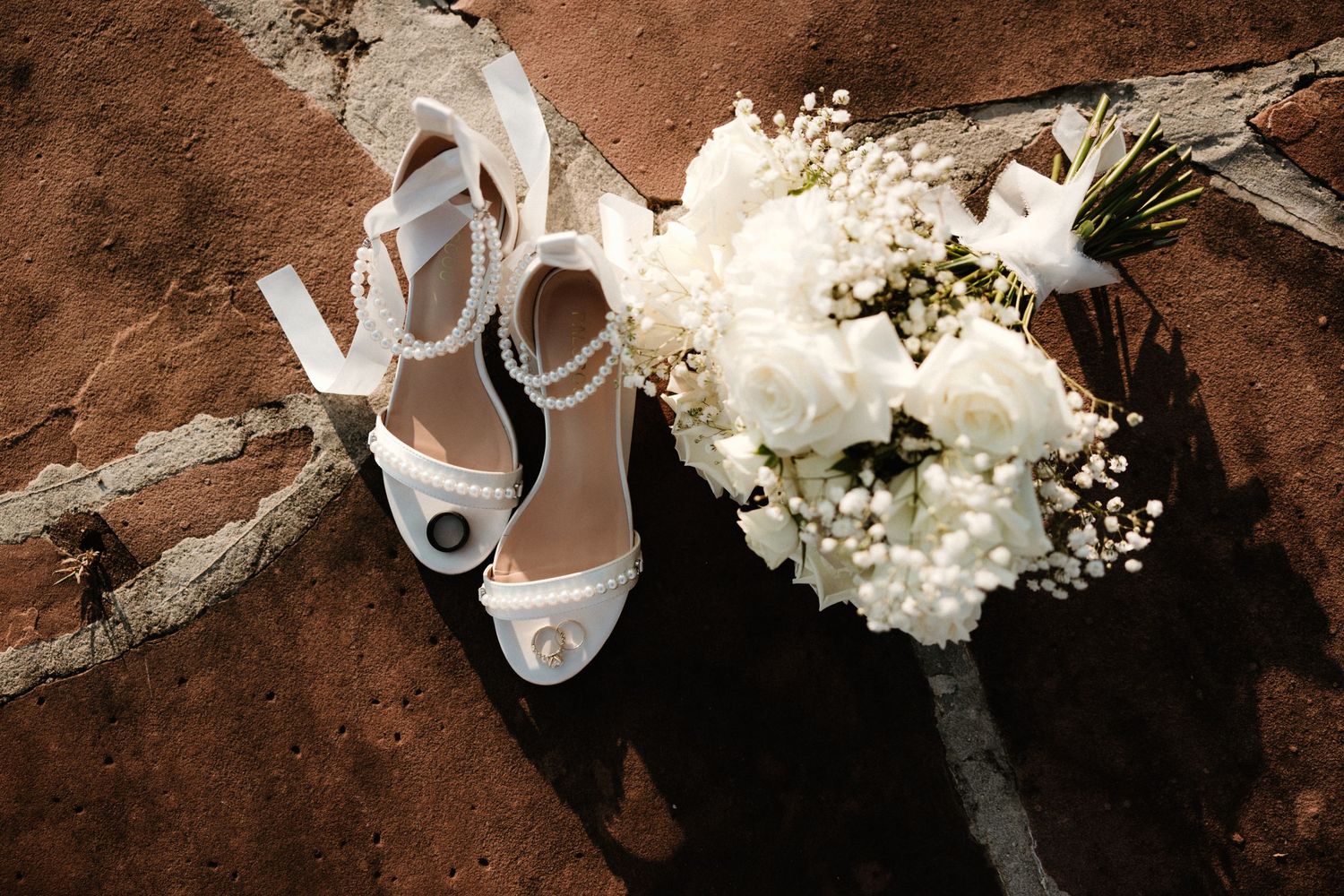 A close-up artistic photo series of elegant white wedding details including shoes, flowers and accessories on a rustic brown background.