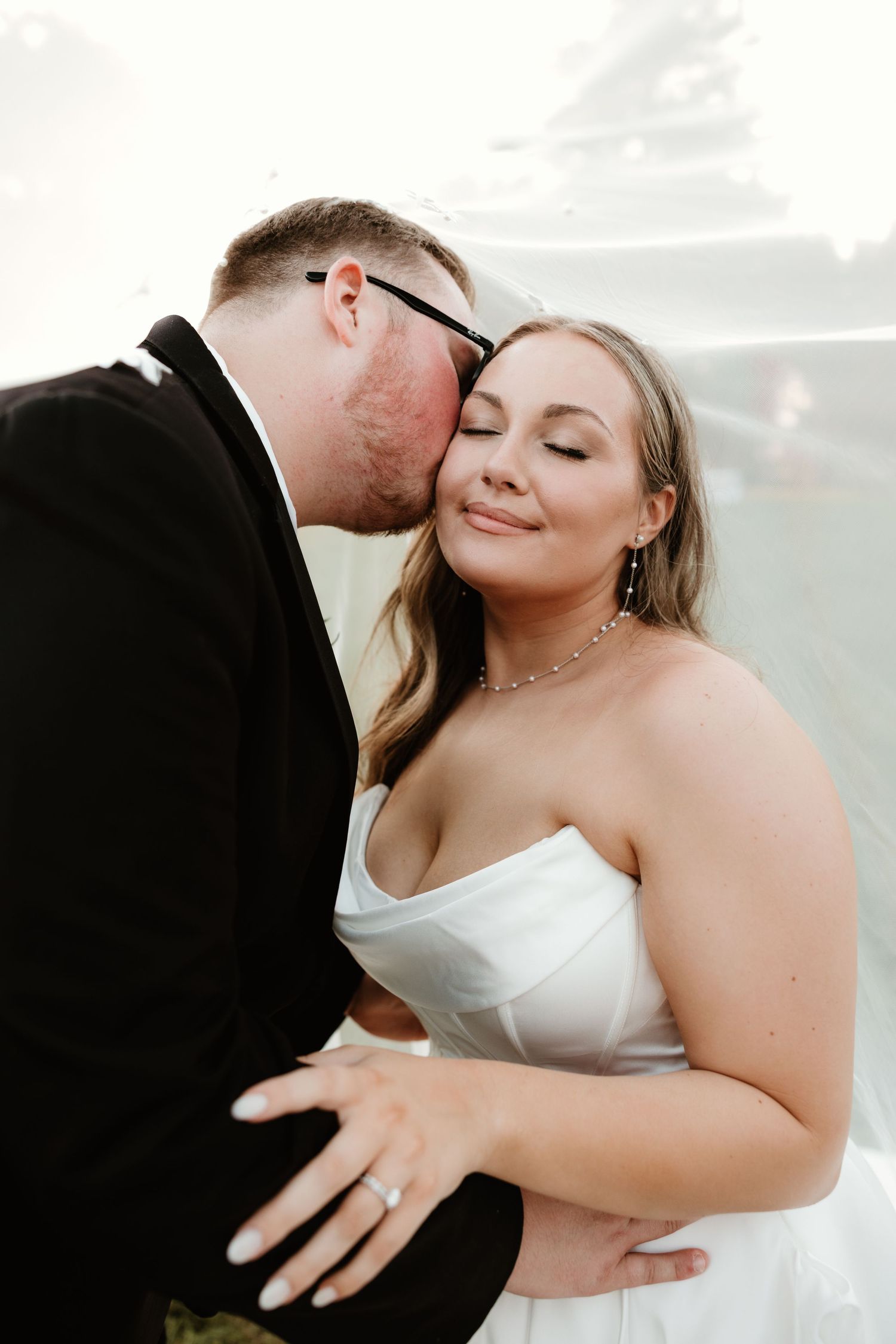 A romantic moment captured between newlyweds sharing tender embraces at their wedding ceremony.