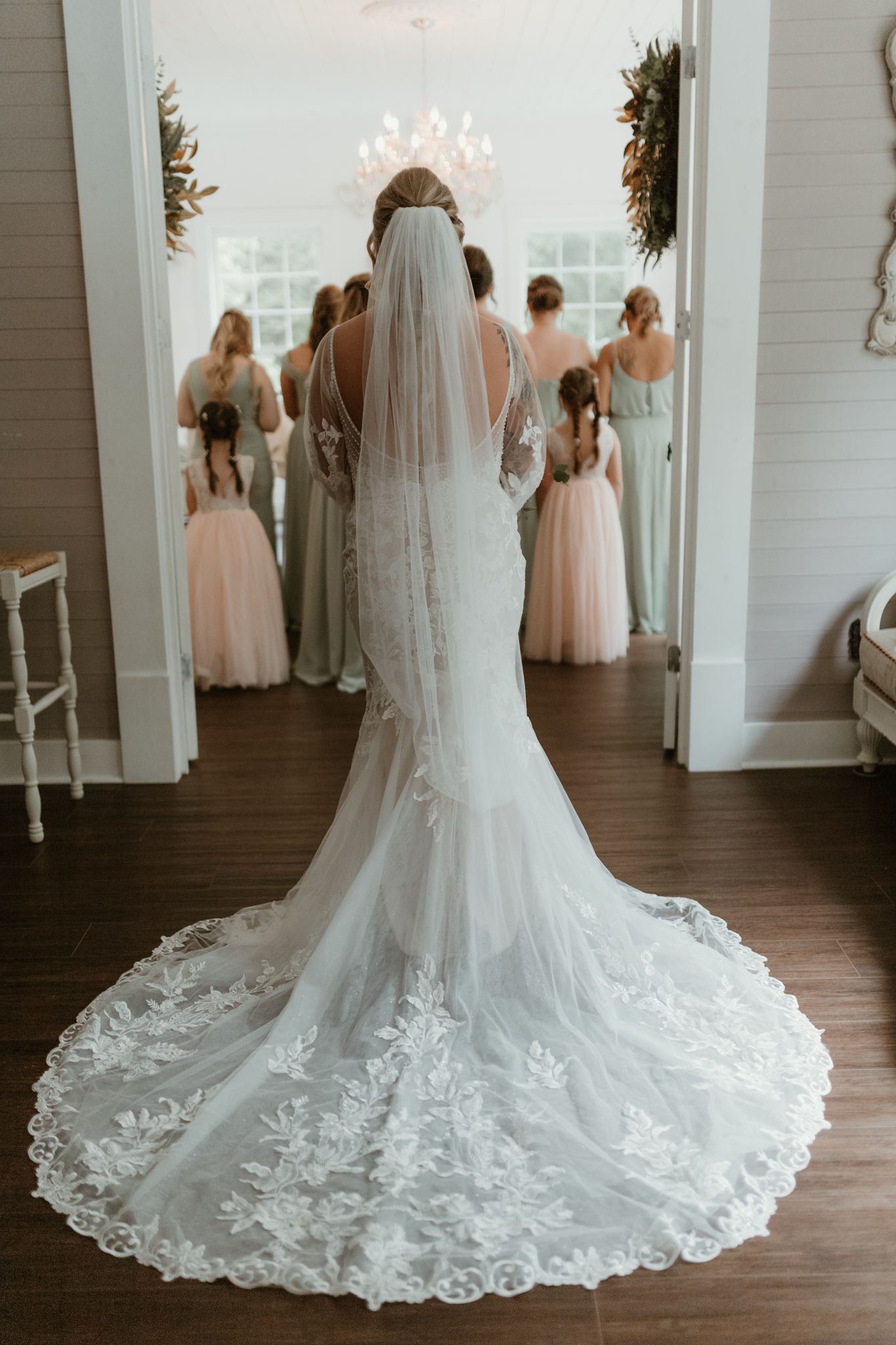 Elegant wedding dress train with intricate lace details spread across dark hardwood floors.