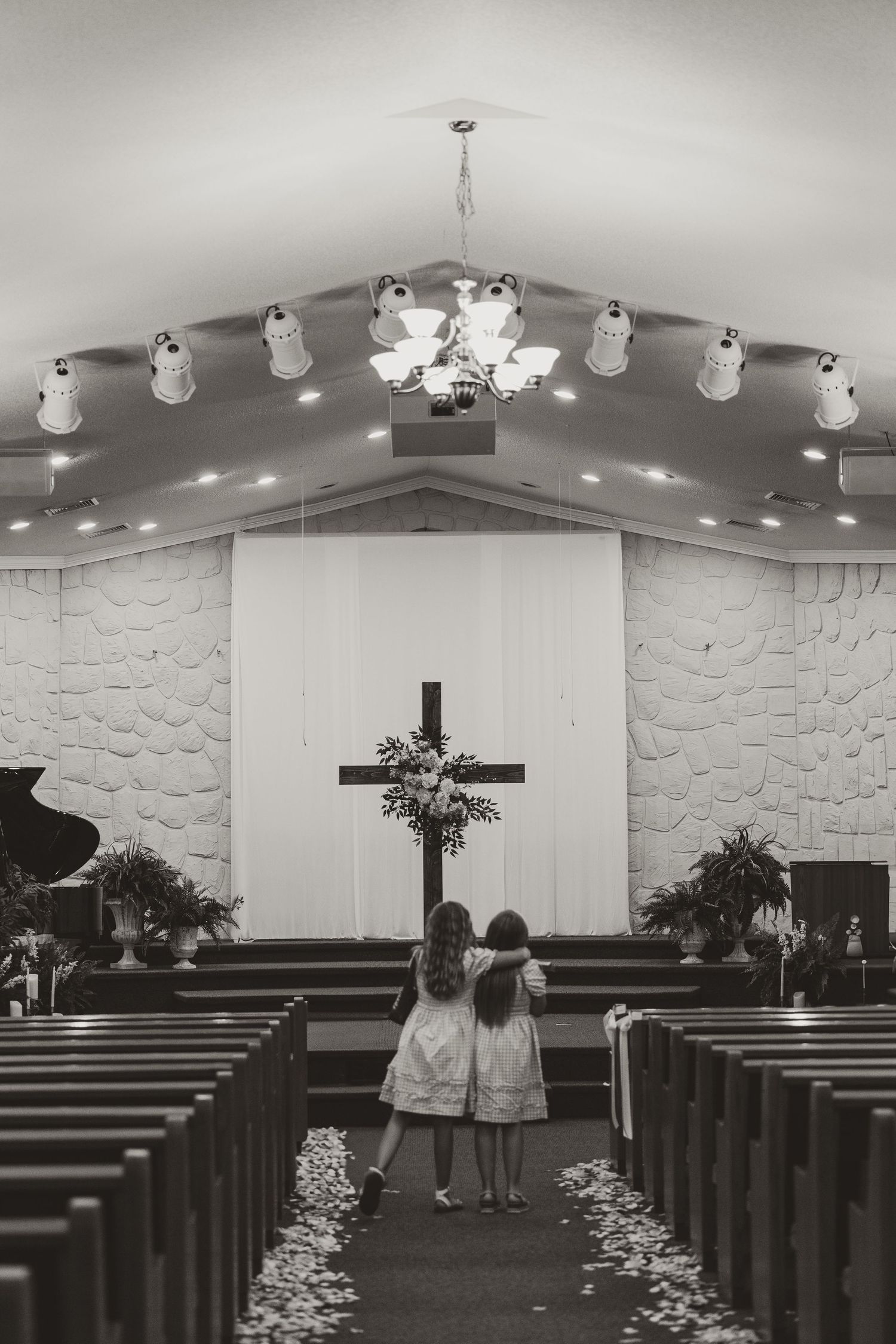 A black and white photo series shows the interior of a modern church sanctuary with white walls and wooden pews.