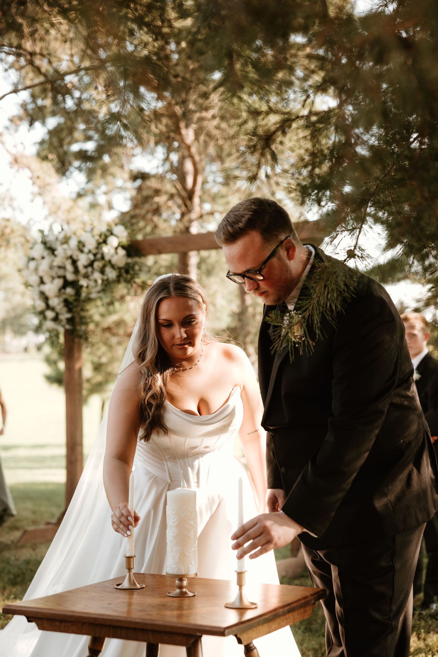 A wedding couple shares an intimate moment during golden hour while leaning over a wooden table outdoors.