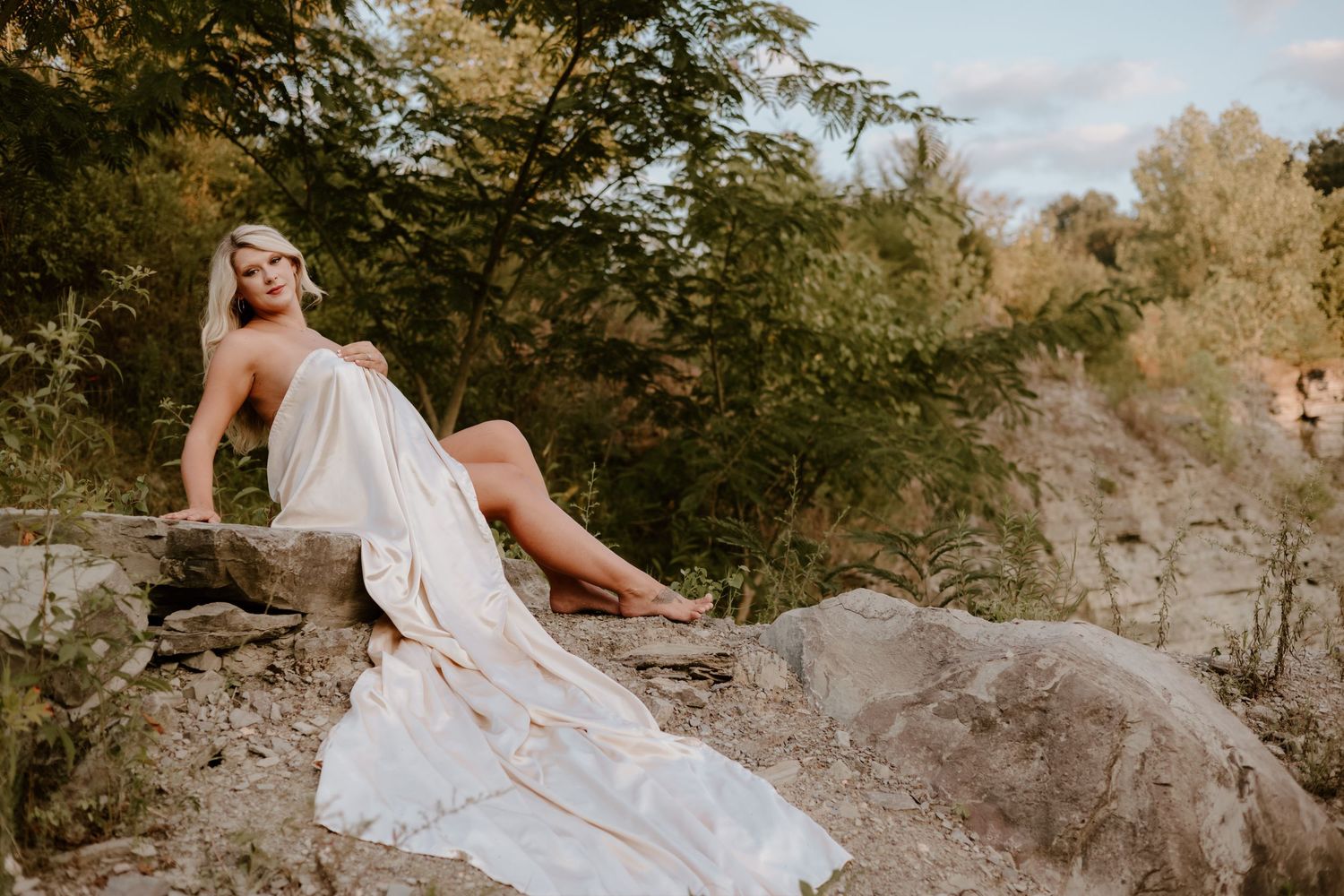 A romantic photo session featuring a flowing white dress against rocky cliffs in warm sunlight.