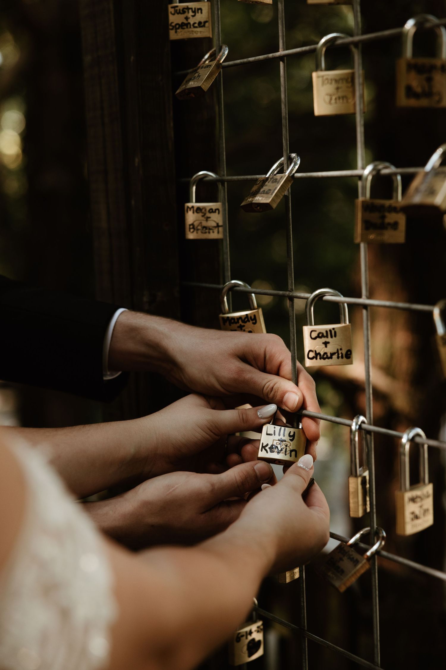 Close-up of hands placing small locks on a metal grid rack symbolizing love or commitment.
