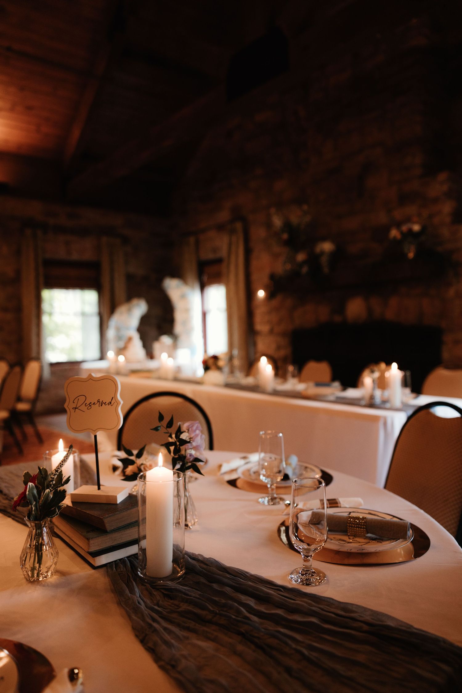 Candles illuminate elegant table settings at a rustic venue with brick walls and white linens creating an intimate atmosphere.