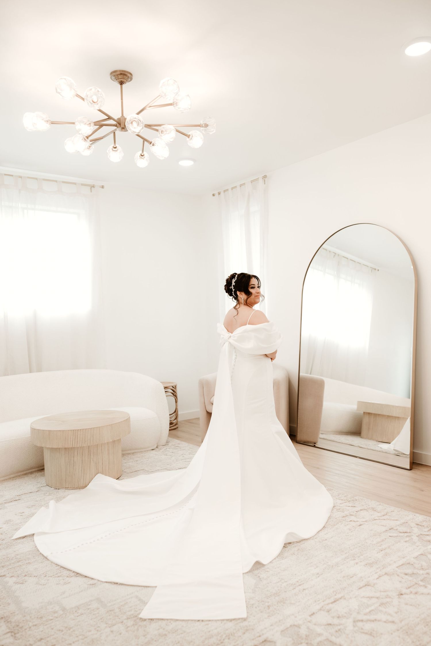 Minimalist white bridal suite with round mirror and flowing wedding dress.