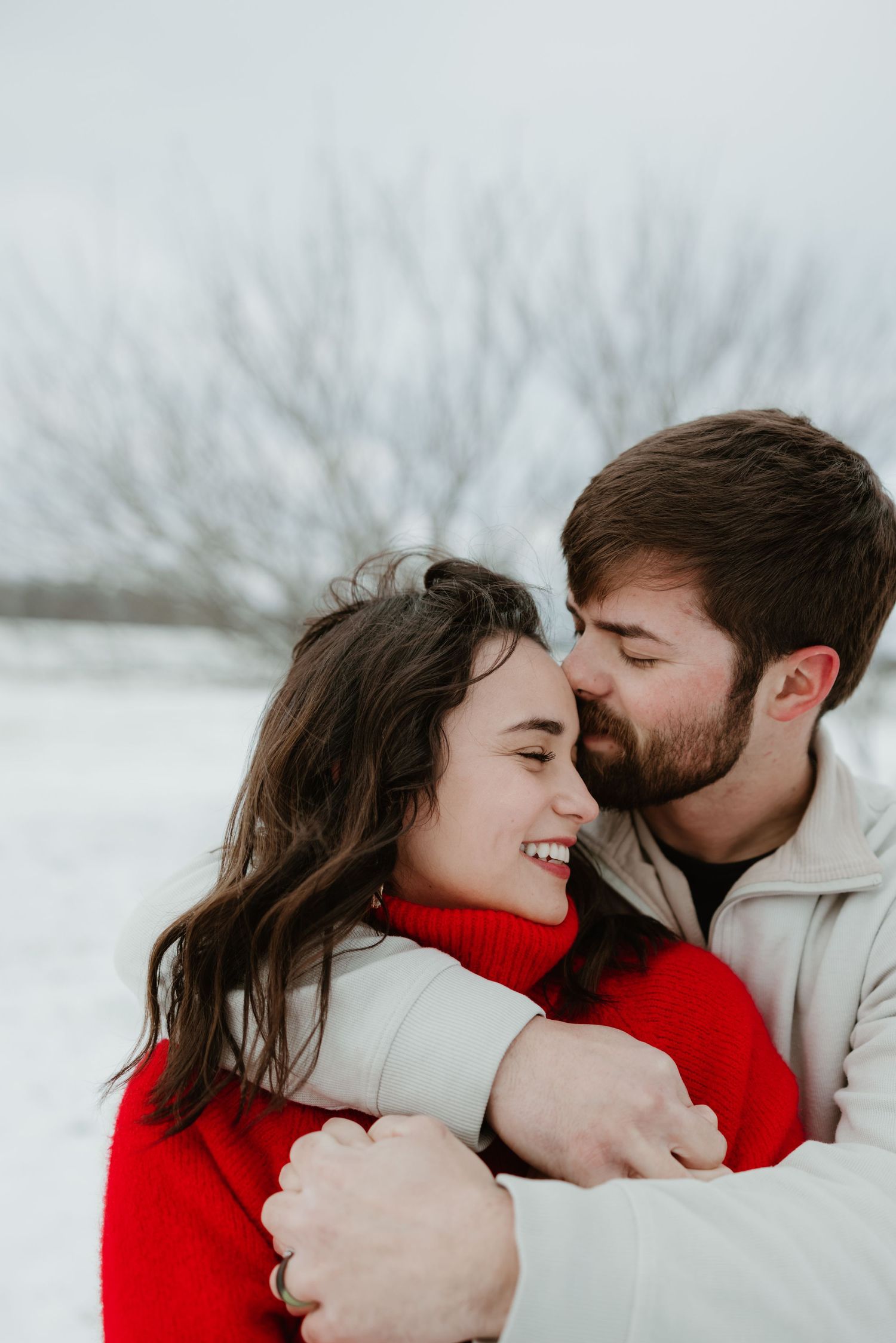 Cozy winter couple photos showing playful intimate moments in the snow.