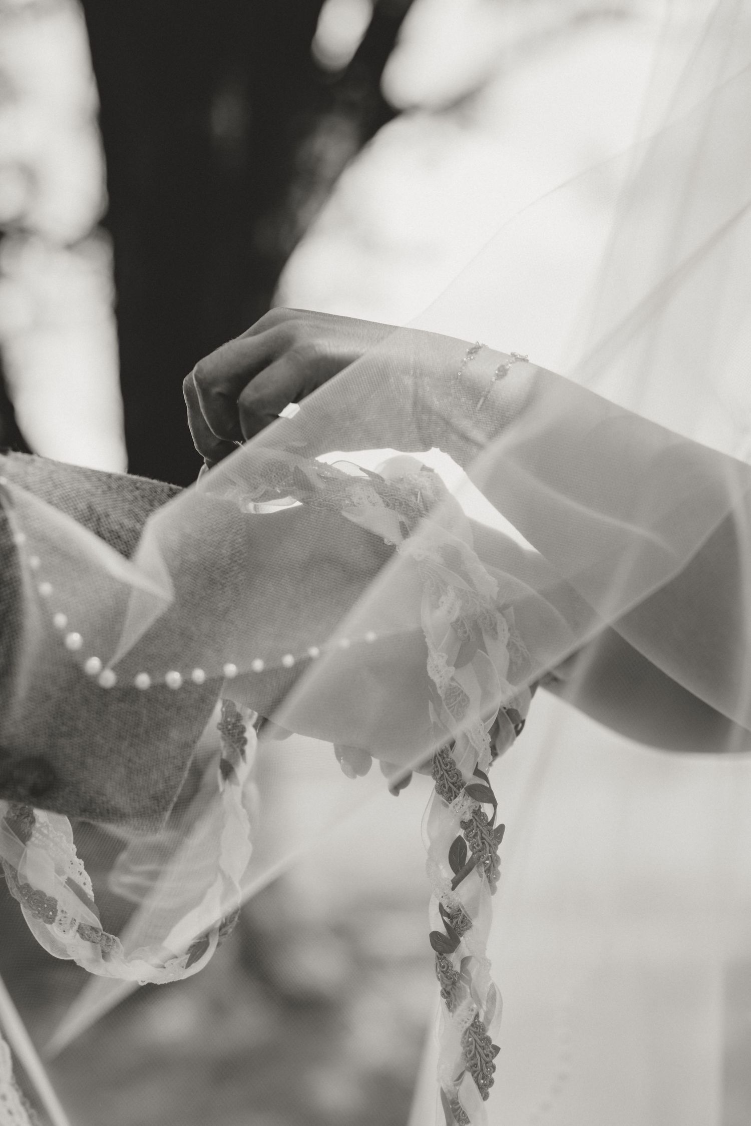 Close-up detail of a flowing white wedding veil with delicate lace embellishments in black and white.