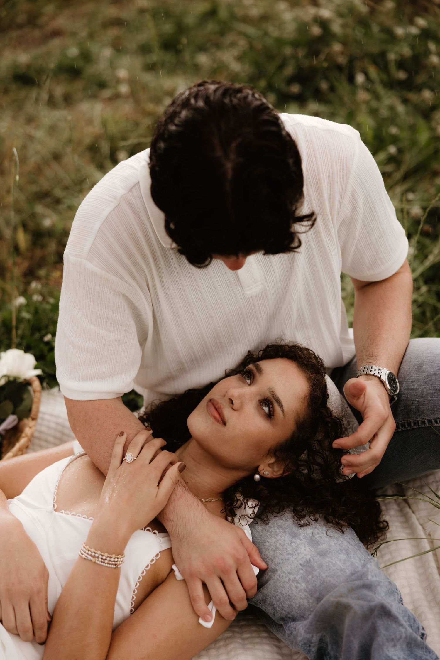 Intimate portrait of couple laying on blanket in outdoor setting.