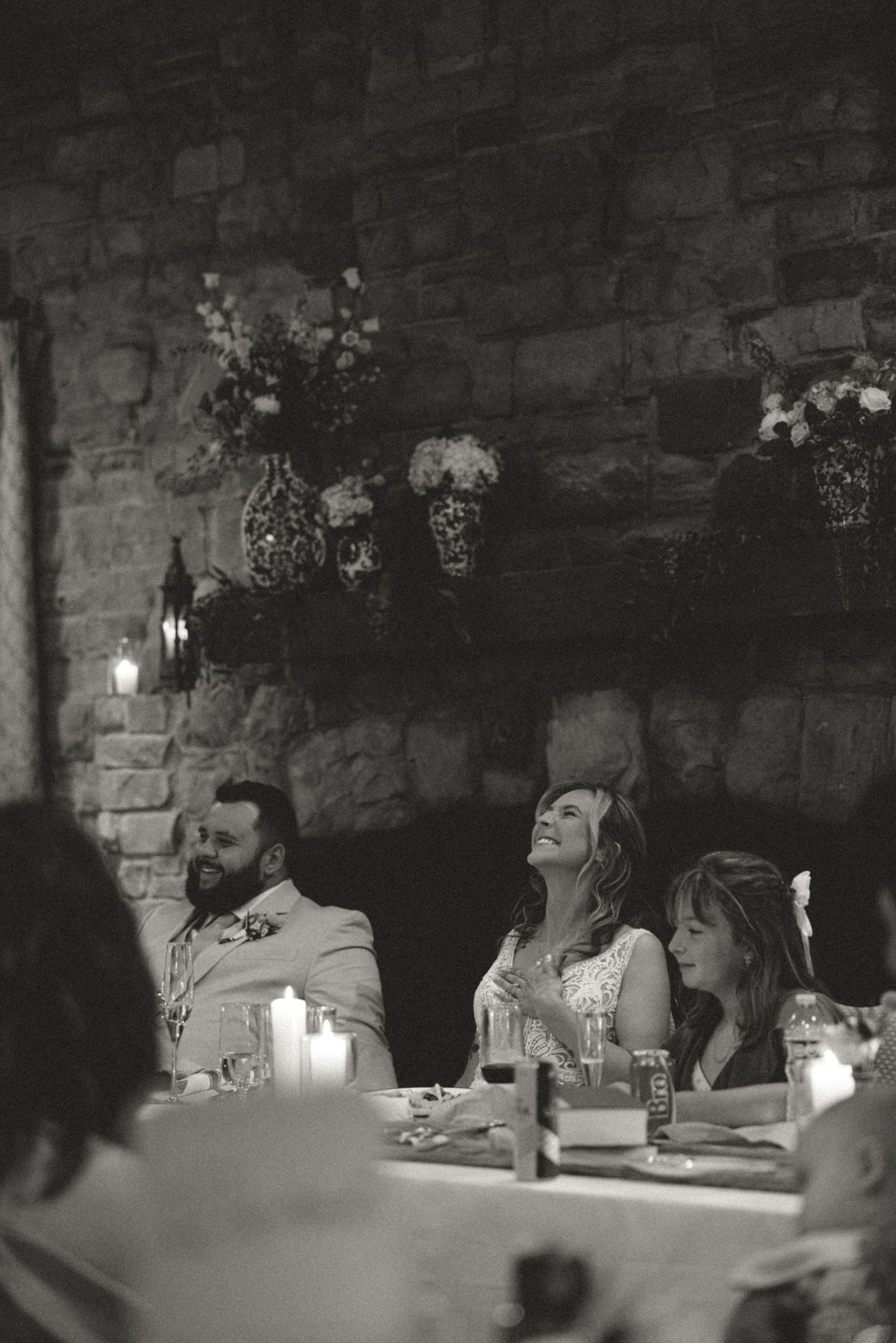 Candlelit dinner reception at rustic stone venue with guests seated at long tables.