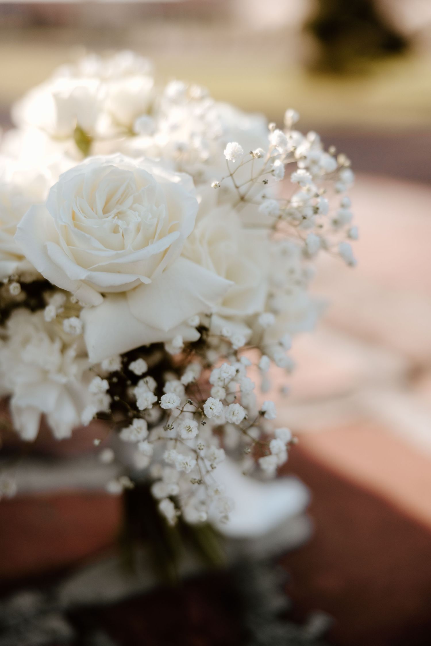 Delicate white roses and baby's breath floral arrangement in soft focus.