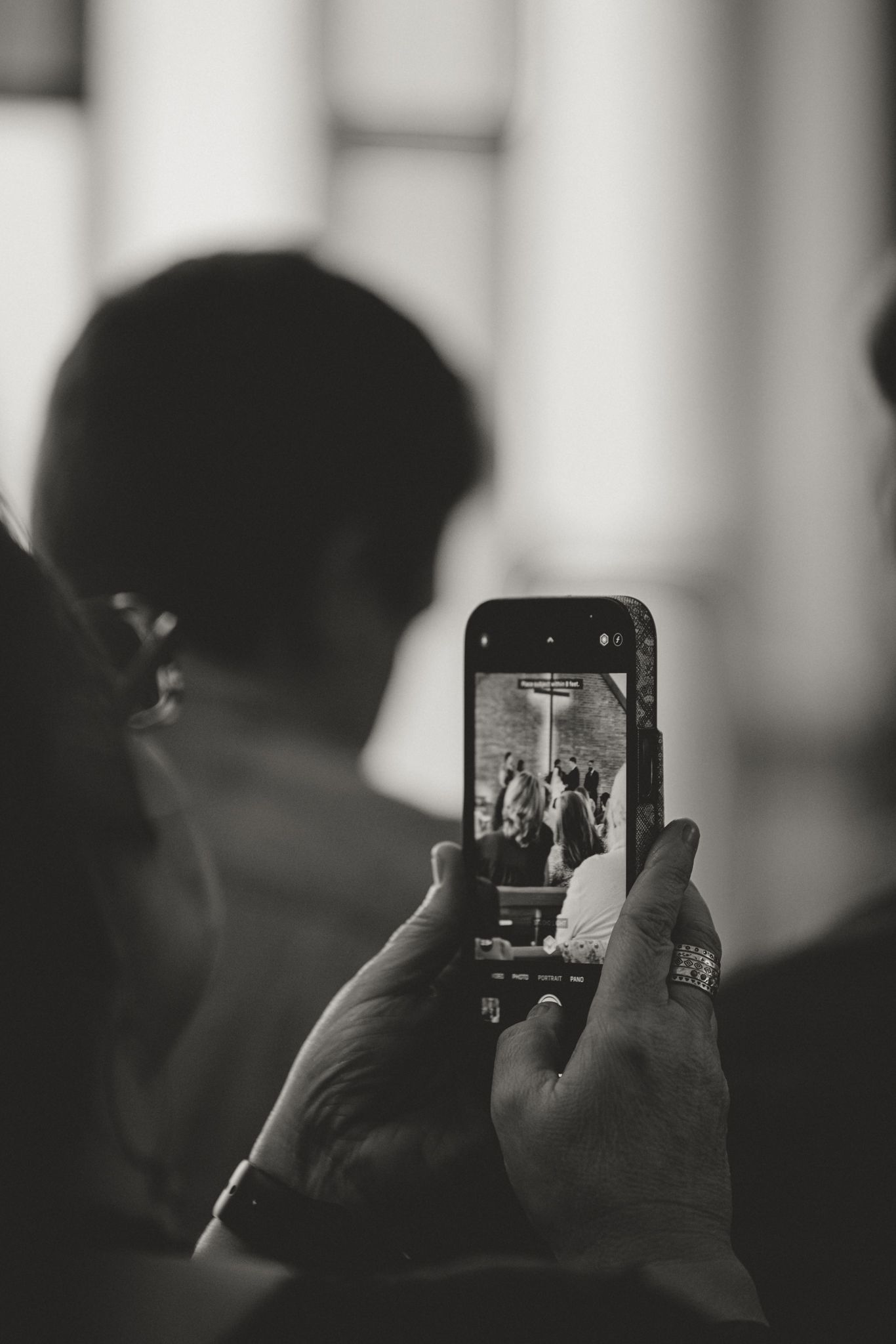 Silhouetted figure taking photos with a smartphone in a dimly lit environment.