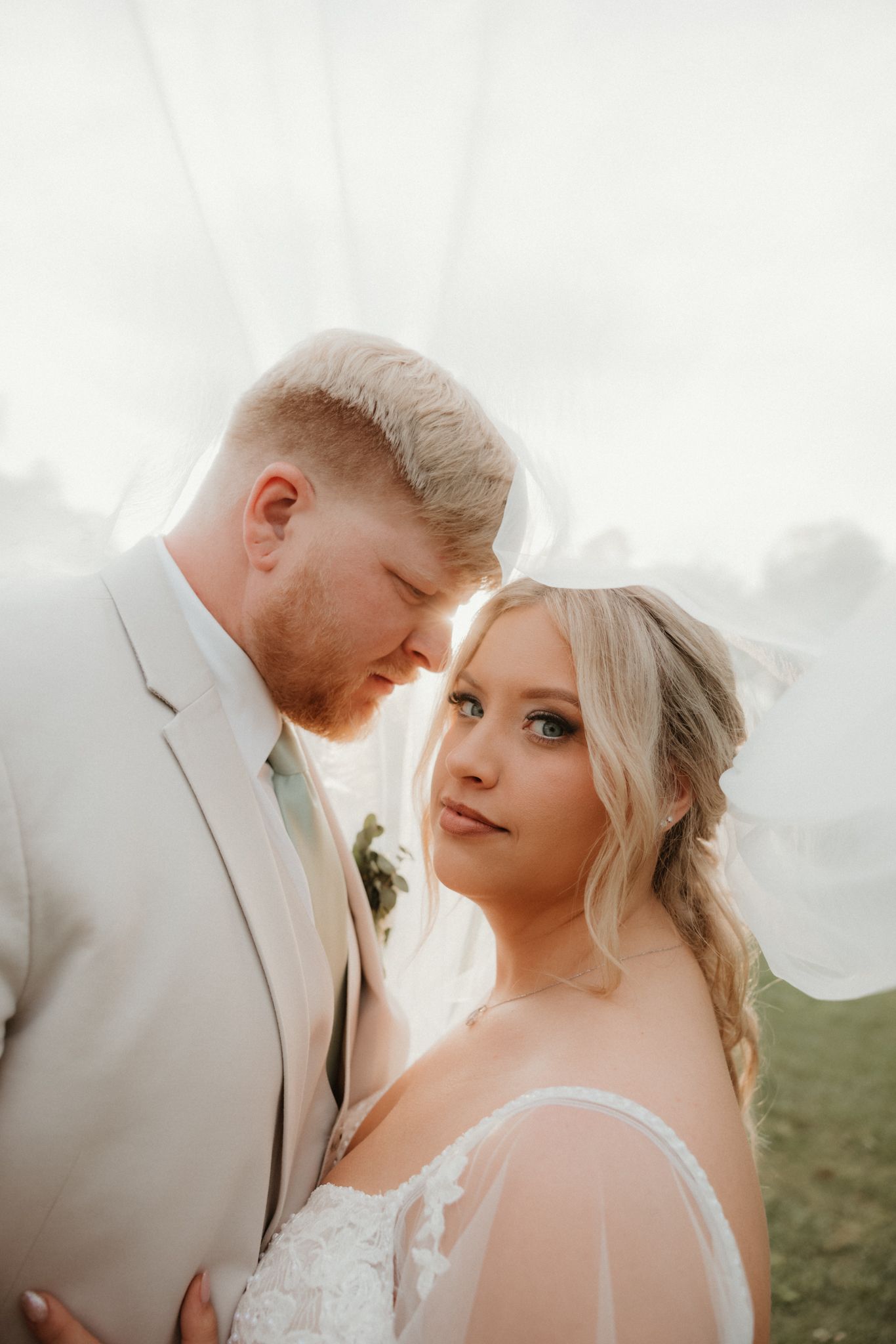 Beautiful wedding portrait captured in soft natural light with a light beige suit and white bridal gown.